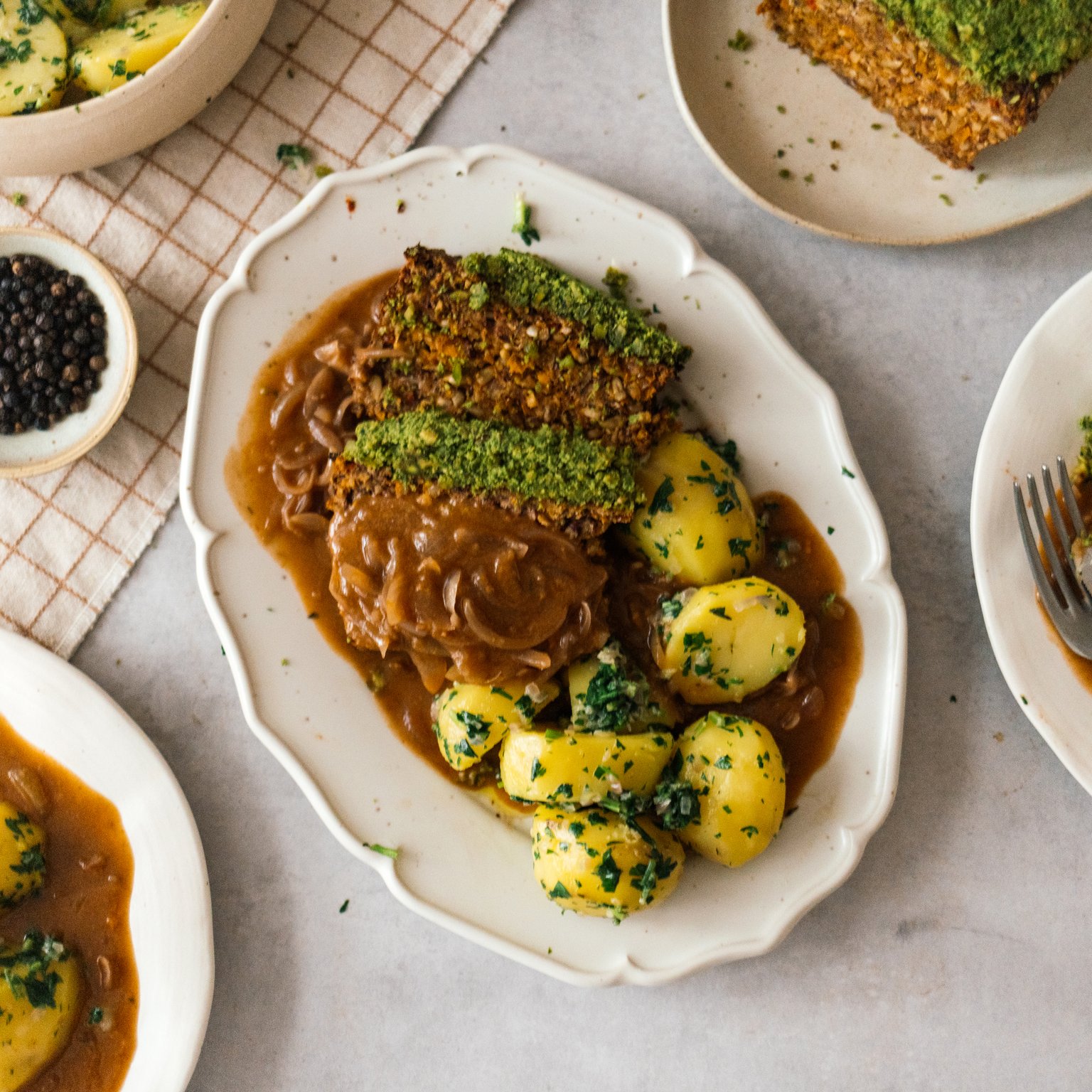 Veganer Braten mit Kräuterkruste, Petersilienkartoffeln und Zwiebelsoße