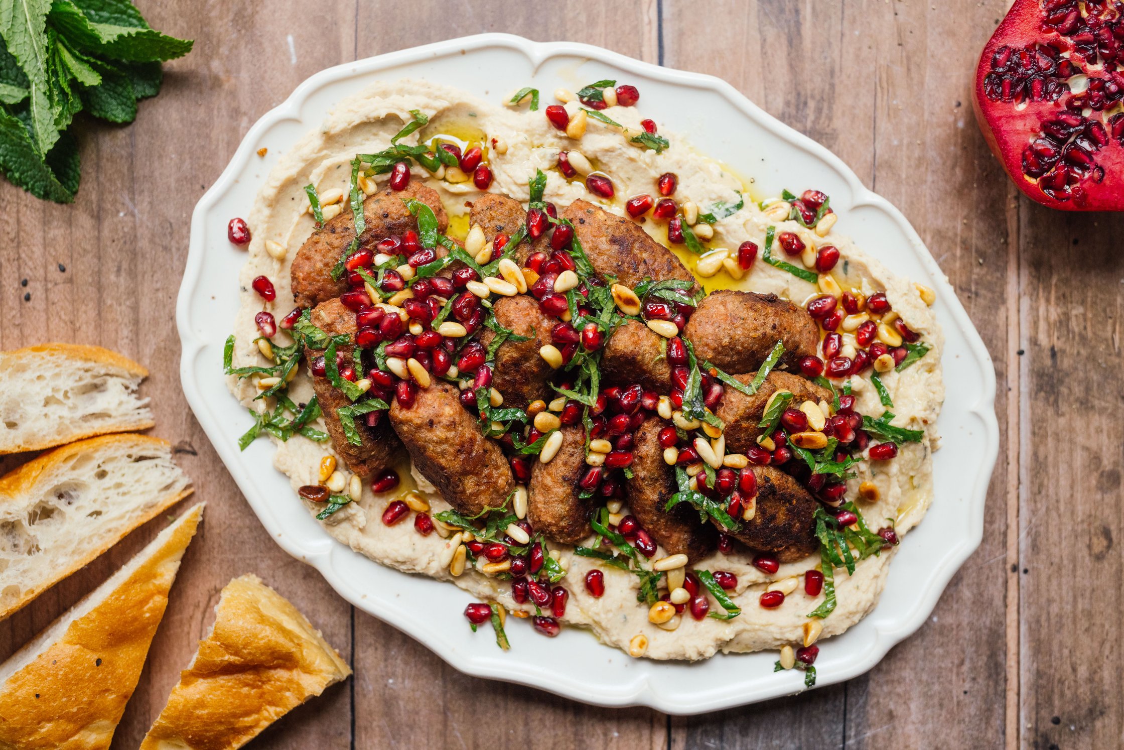 vegan kofta on white bean puree with pomegranate topping served on a platter