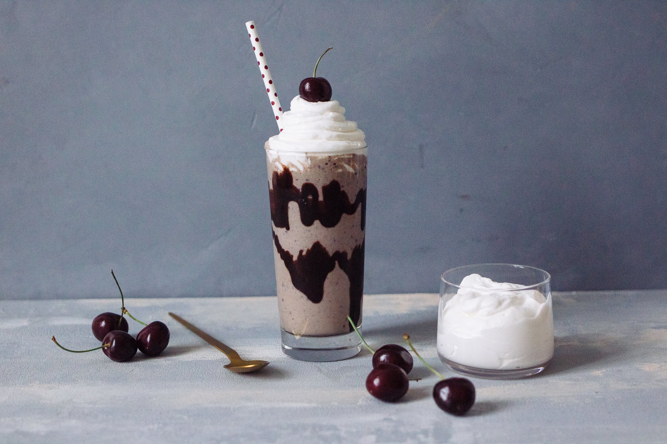 Veganer Kirsch Vanille Milchshake neben einem Gefäß Sahne