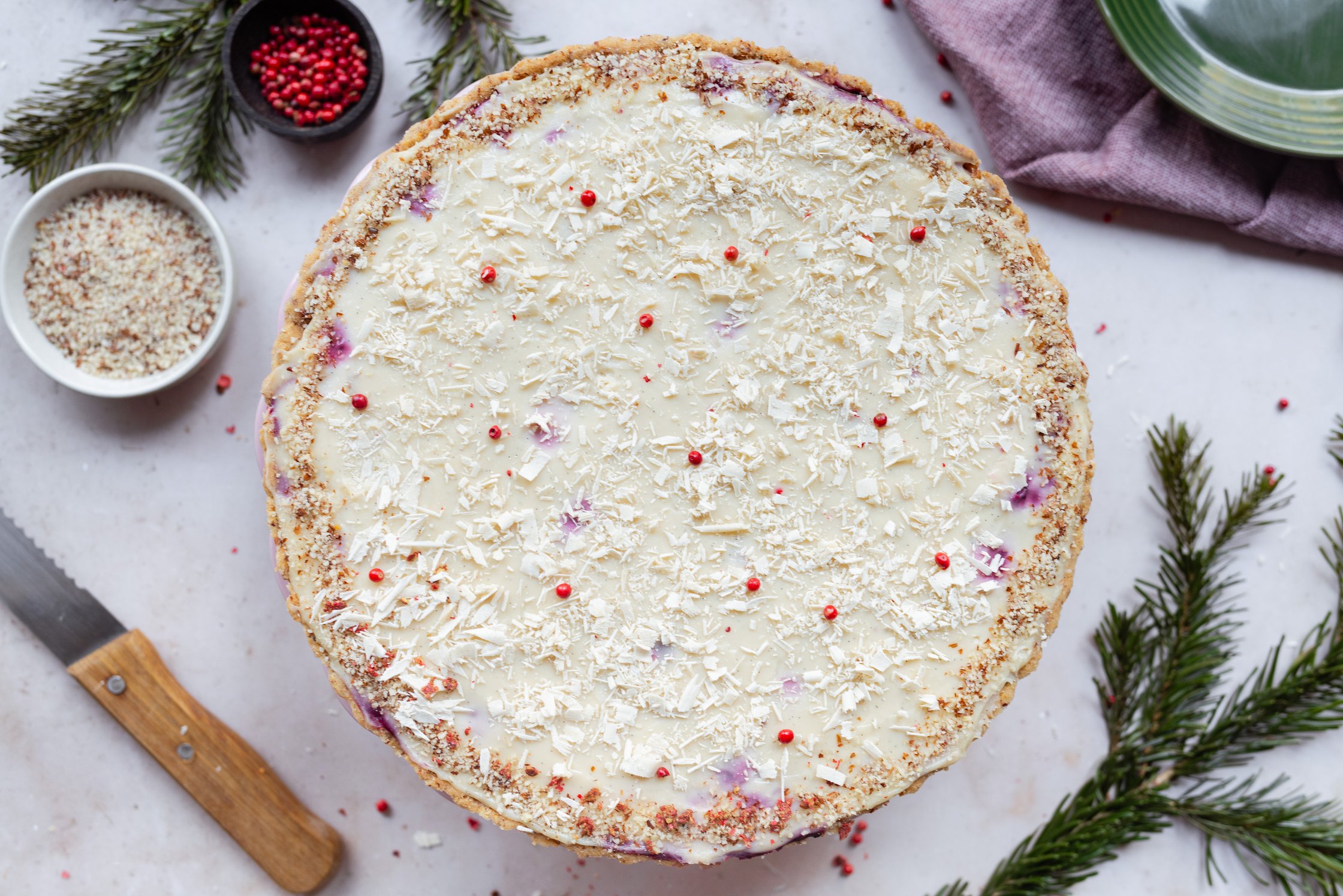 vegane weiße Schokoladentarte mit rosa Pfeffer auf einer Tortenplatte