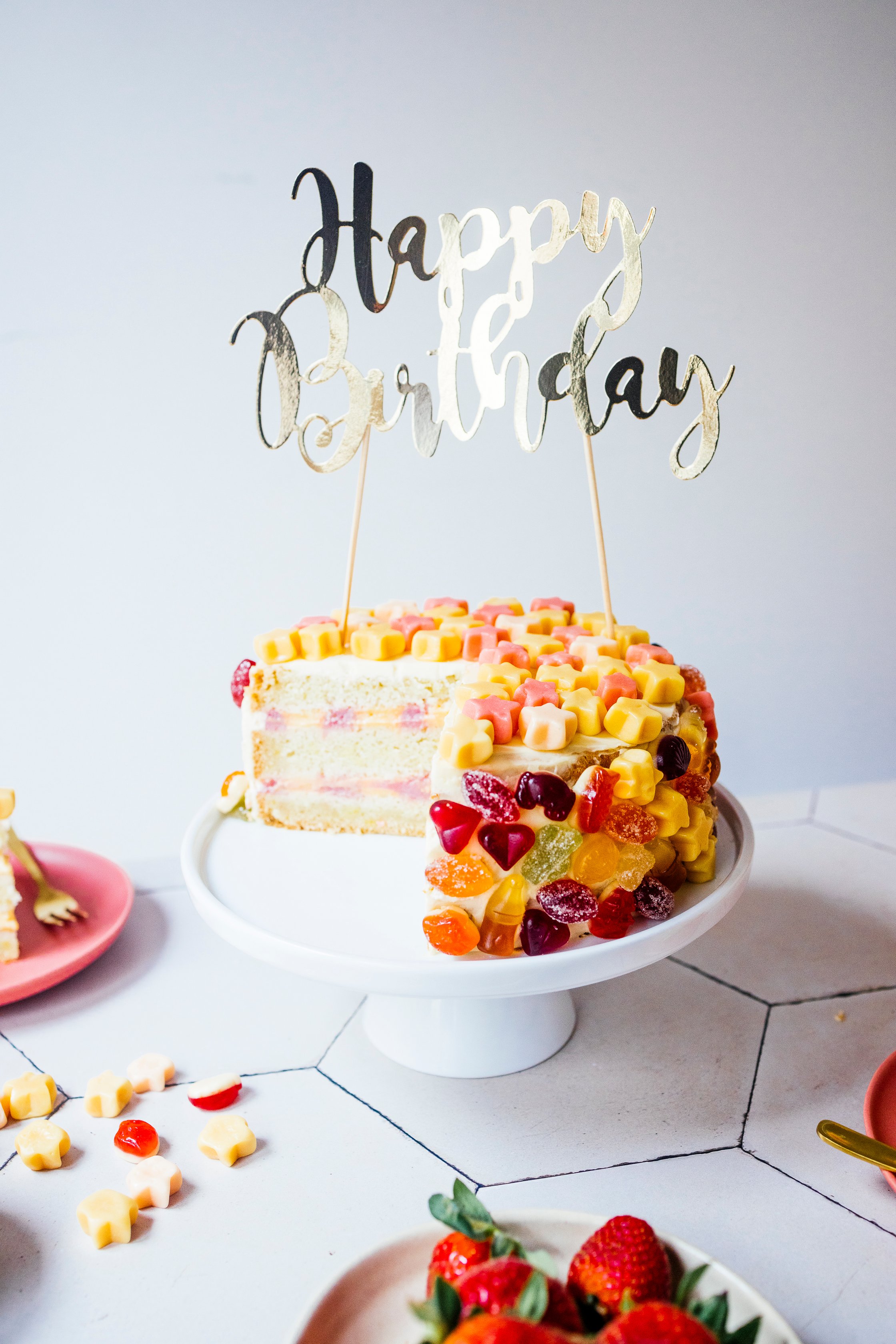 vegan birthday cake decorated with sweets on a cake platter