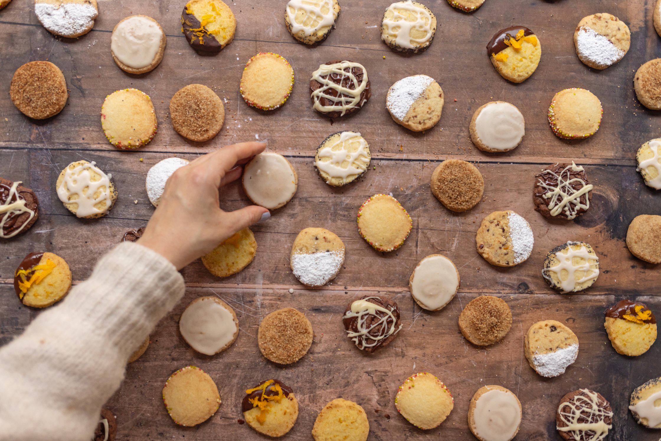 A hand takes a cookie from a table full of vegan christmas cookies