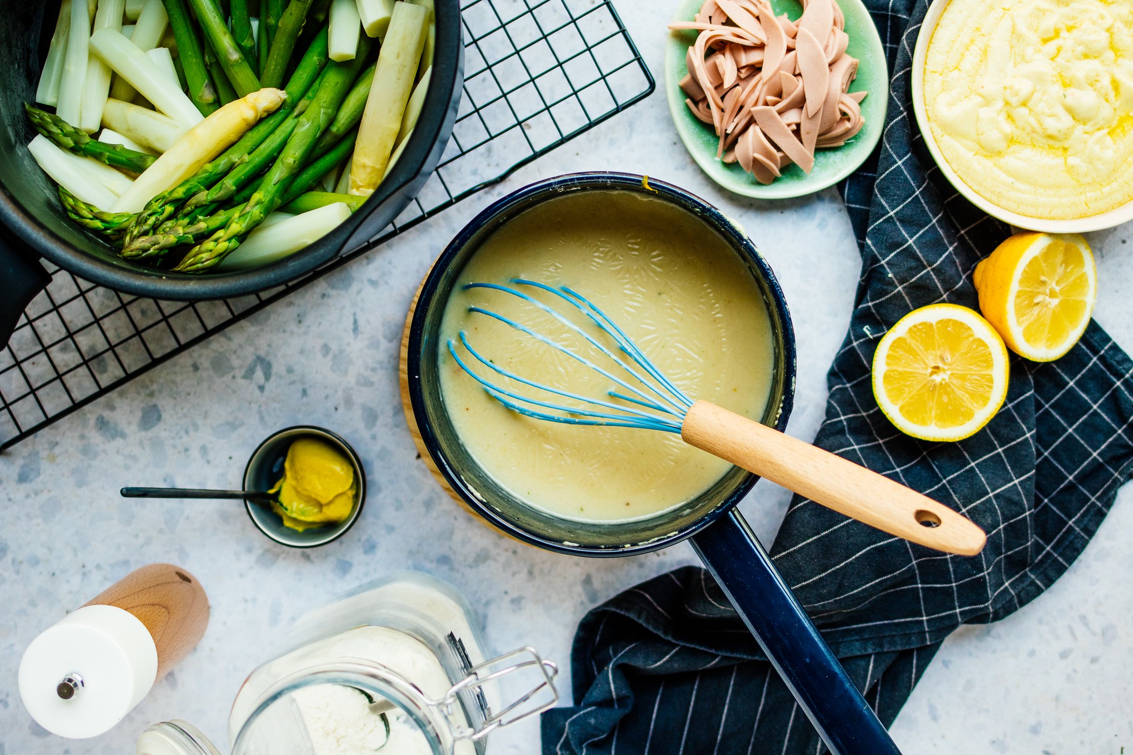 Spargel in einem Topf auf einem Gitter und vegane Sauce Sollandaise in einem Topf
