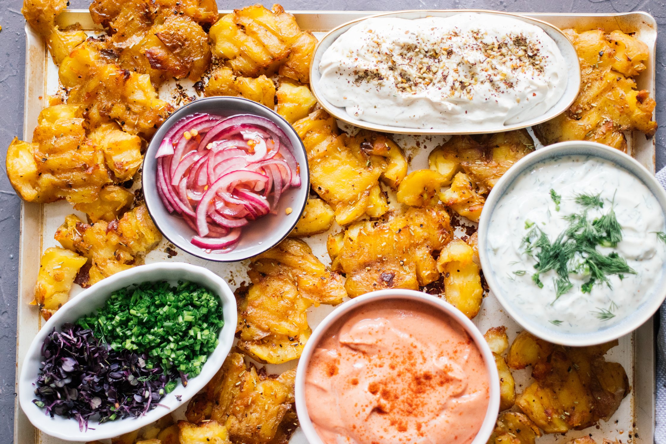 a sheetpan full of Crispy Baked Smashed Potatoes with Vegan Dips