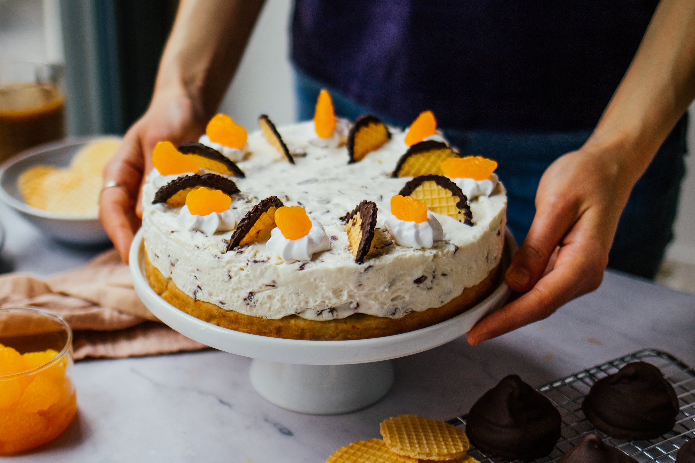 Person hält vegane Schokokuss-Torte mit Mandarinen