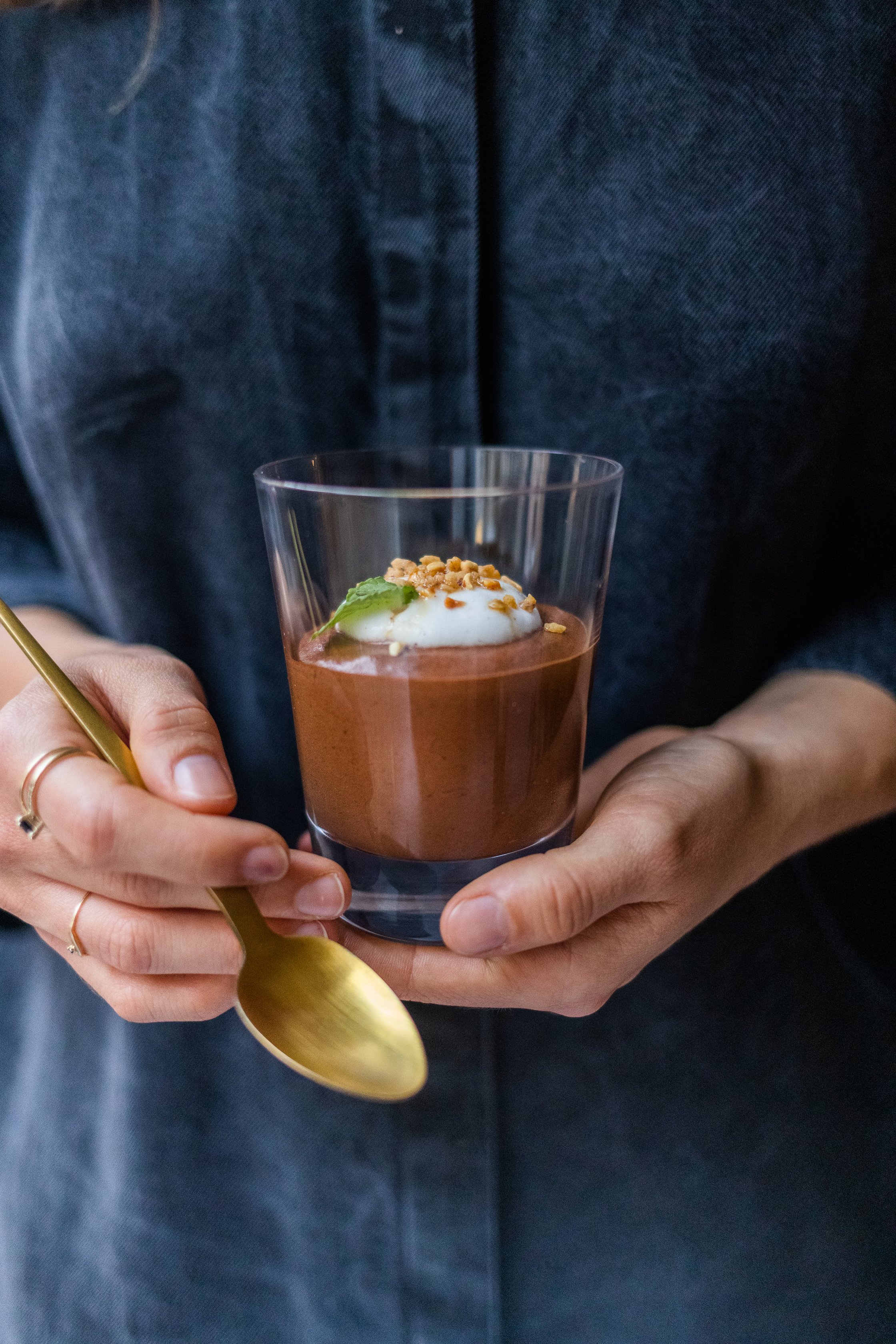 Vegane Mousse au Chocolat ohne Seidentofu im Glas wird in der Hand gehalten.