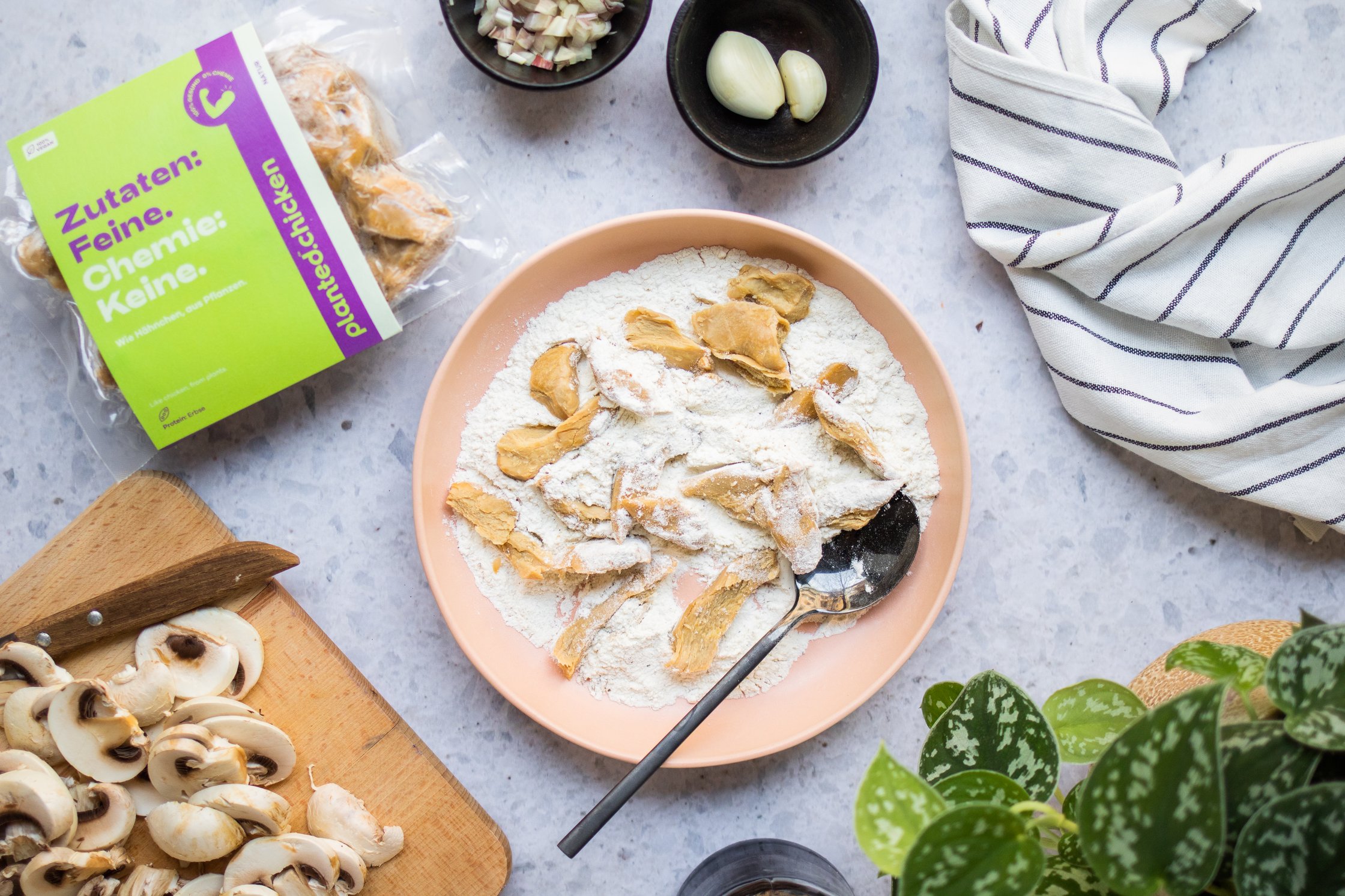 Vegan Chicken on a Plate with Flour, a Pot with Garlic, sliced Mushrooms