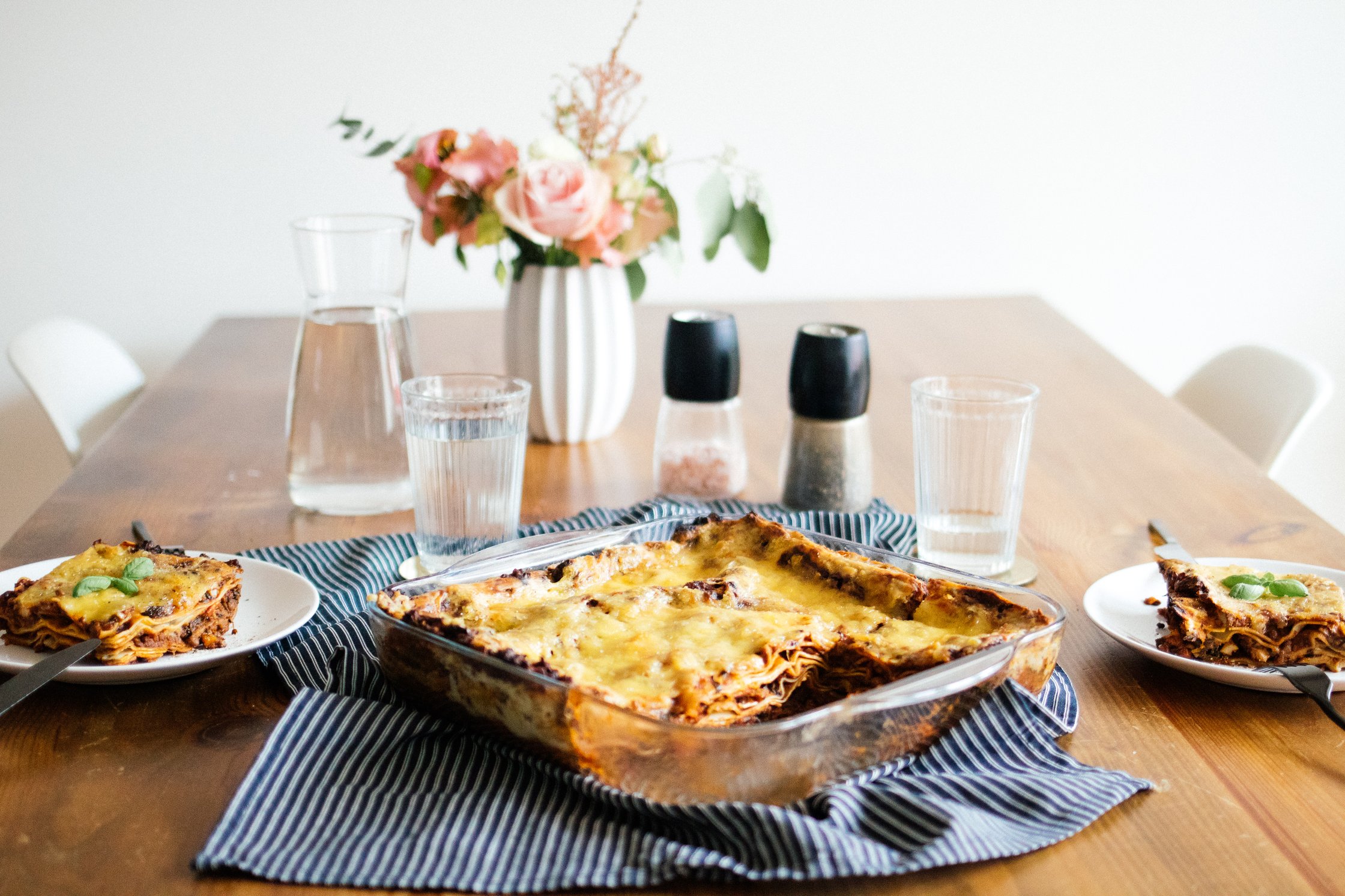 a table with vegan lasagna, glassed and plated