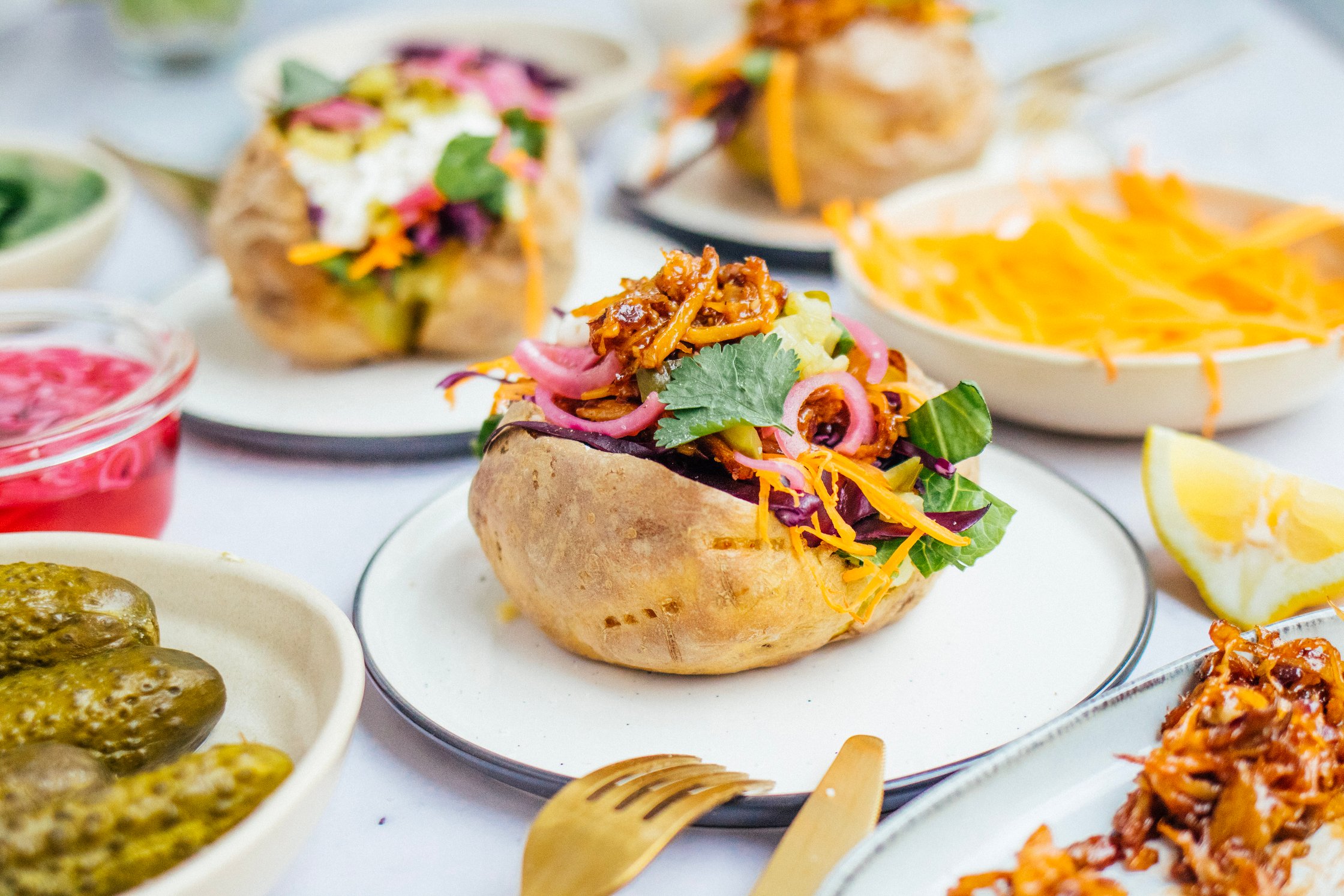 Vegan stuffed kumpir potato on a plate, stuffed with lots of fresh veggies and topped with pulled mushrooms