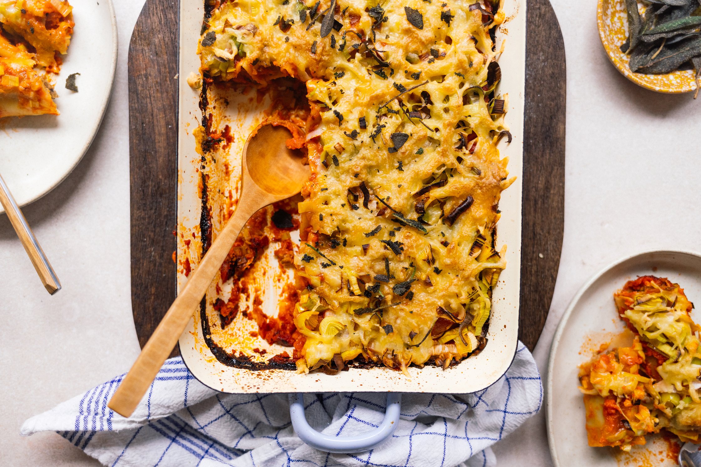 auflaufform mit Cannelloni mit veganer Hackfüllung und Käse-Lauch-Topping auf dem tisch