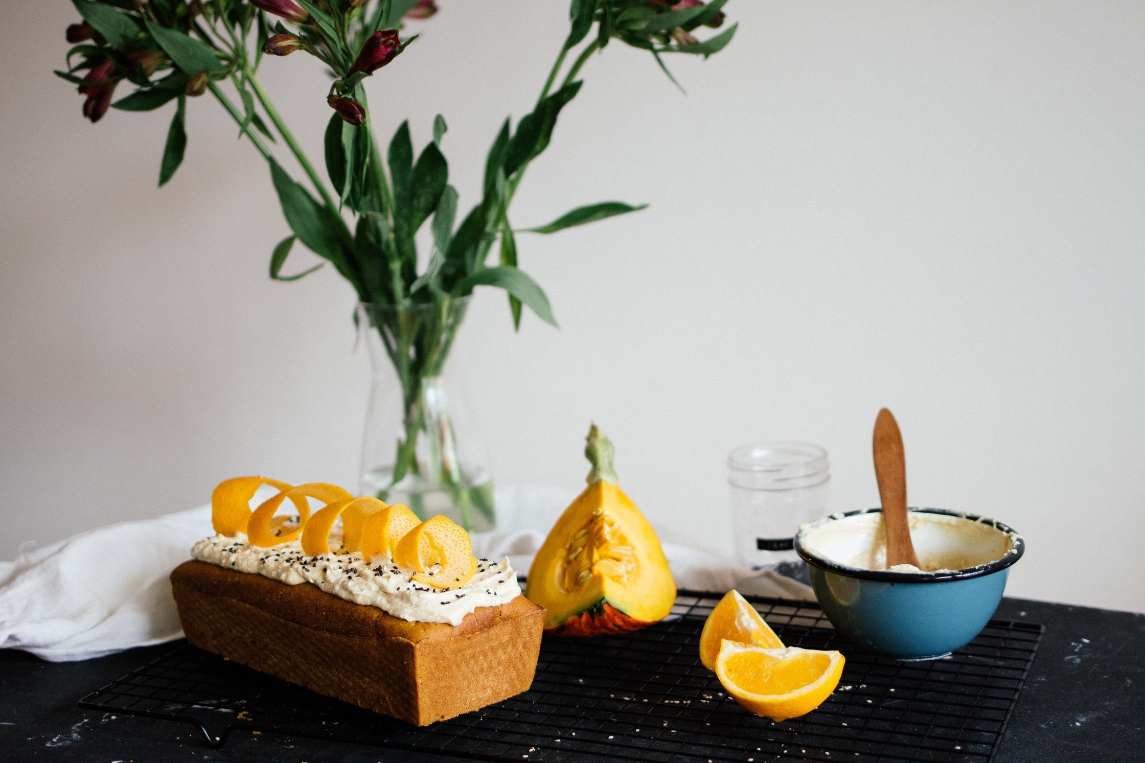 vegan pumpkin cake next to fresh flowers and oranges