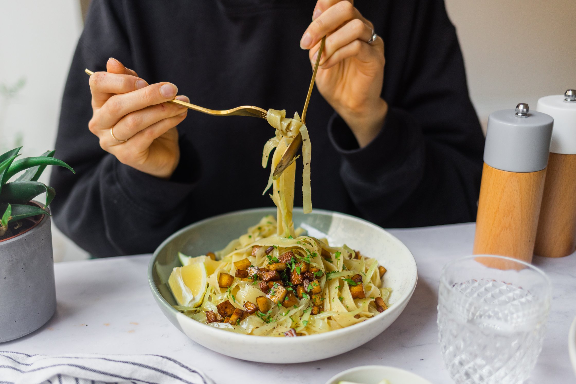 Vegan cabbage and onion pasta with smoked tofu topping is eaten.