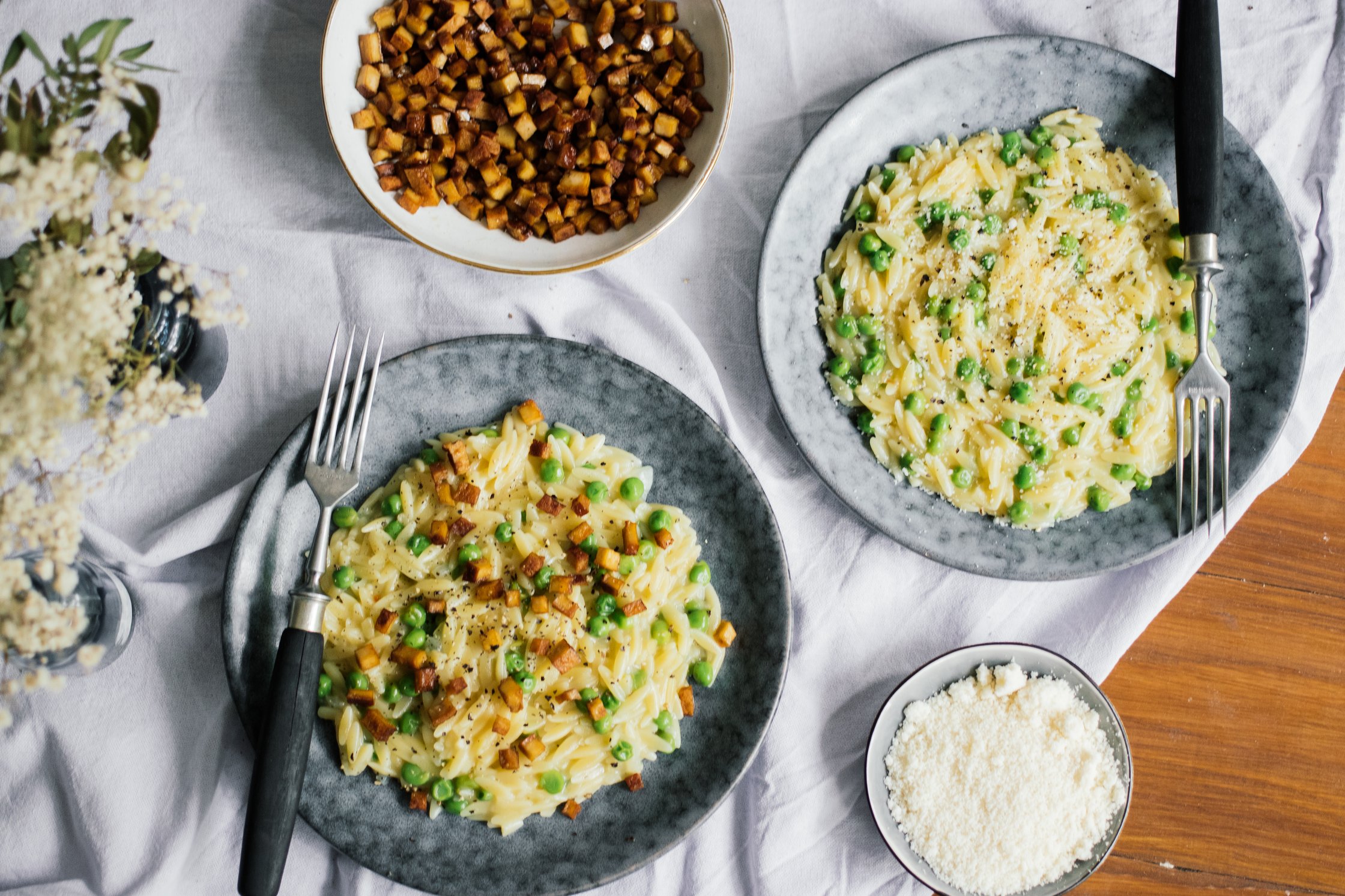Veganes Orzotto mit Erbsen und Räuchertofu auf tellern für zwei personen