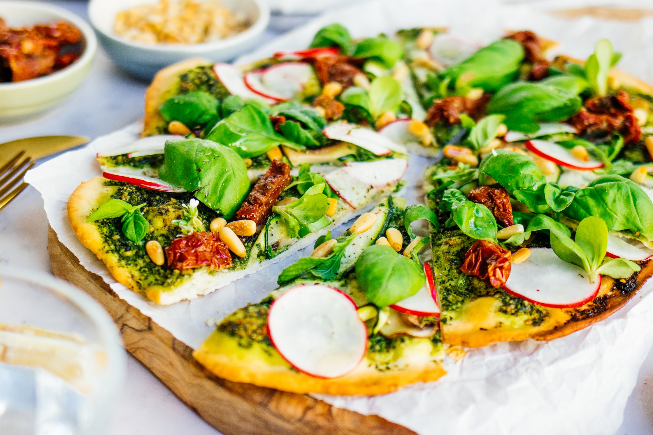 vegane Pesto-Pizza auf Holzbrett