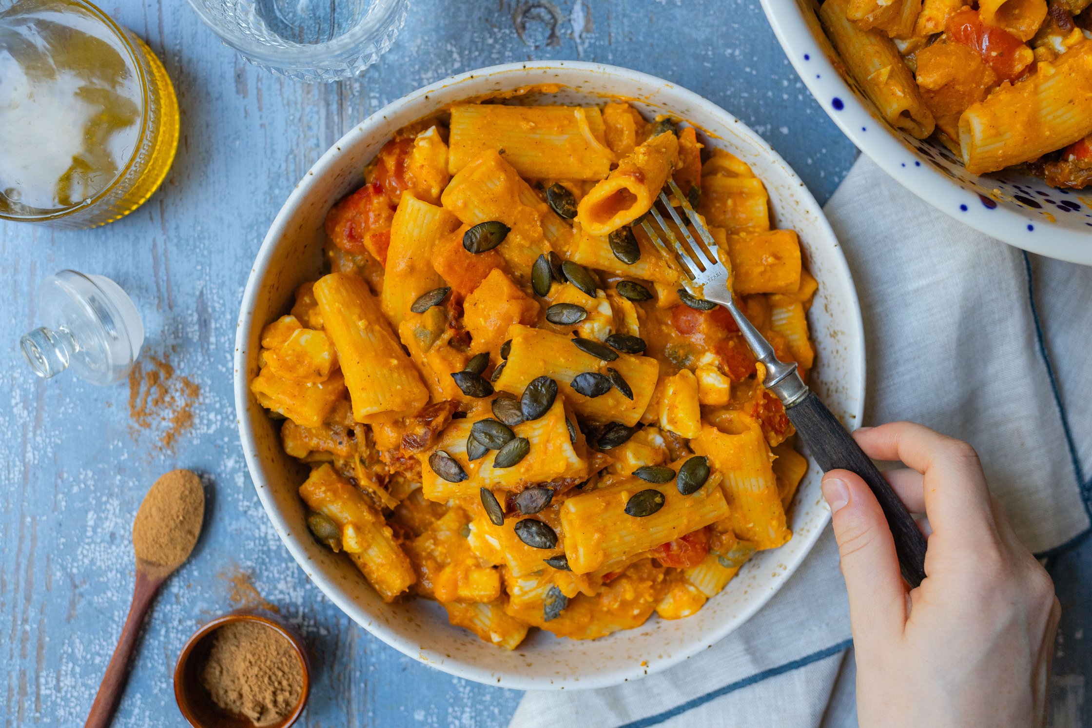 cremige vegane Kürbis-Pasta mit Tomate und Feta auf einem tiefen Teller