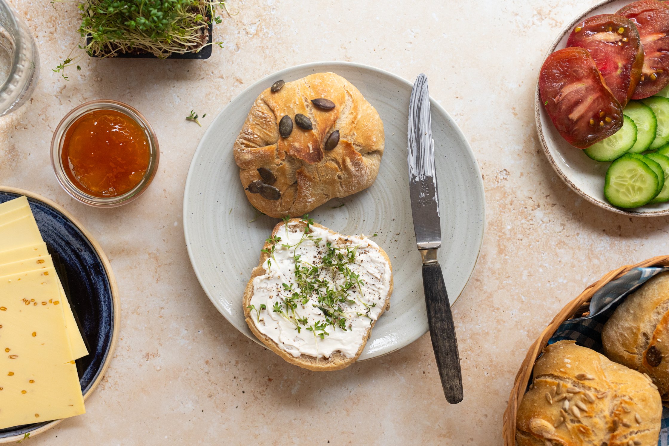 a sliced homemade Sunday roll with vegan cream cheese and cress on a plate