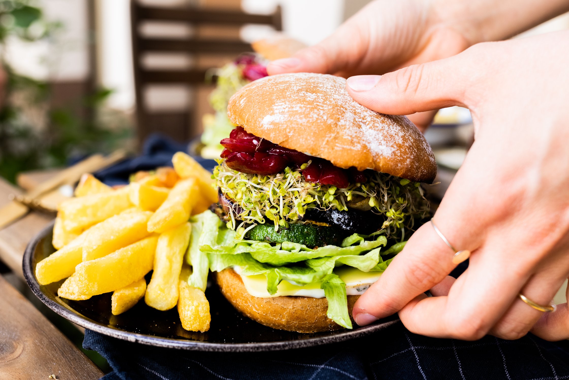 Veganer Grillgemüseburger im Garten auf einem Tisch mit Pommes Fritten