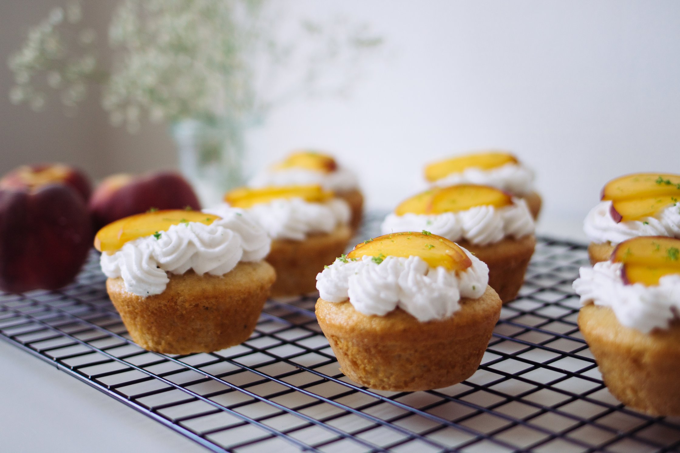 vegan stuffed peach cupcakes on a black baking grid