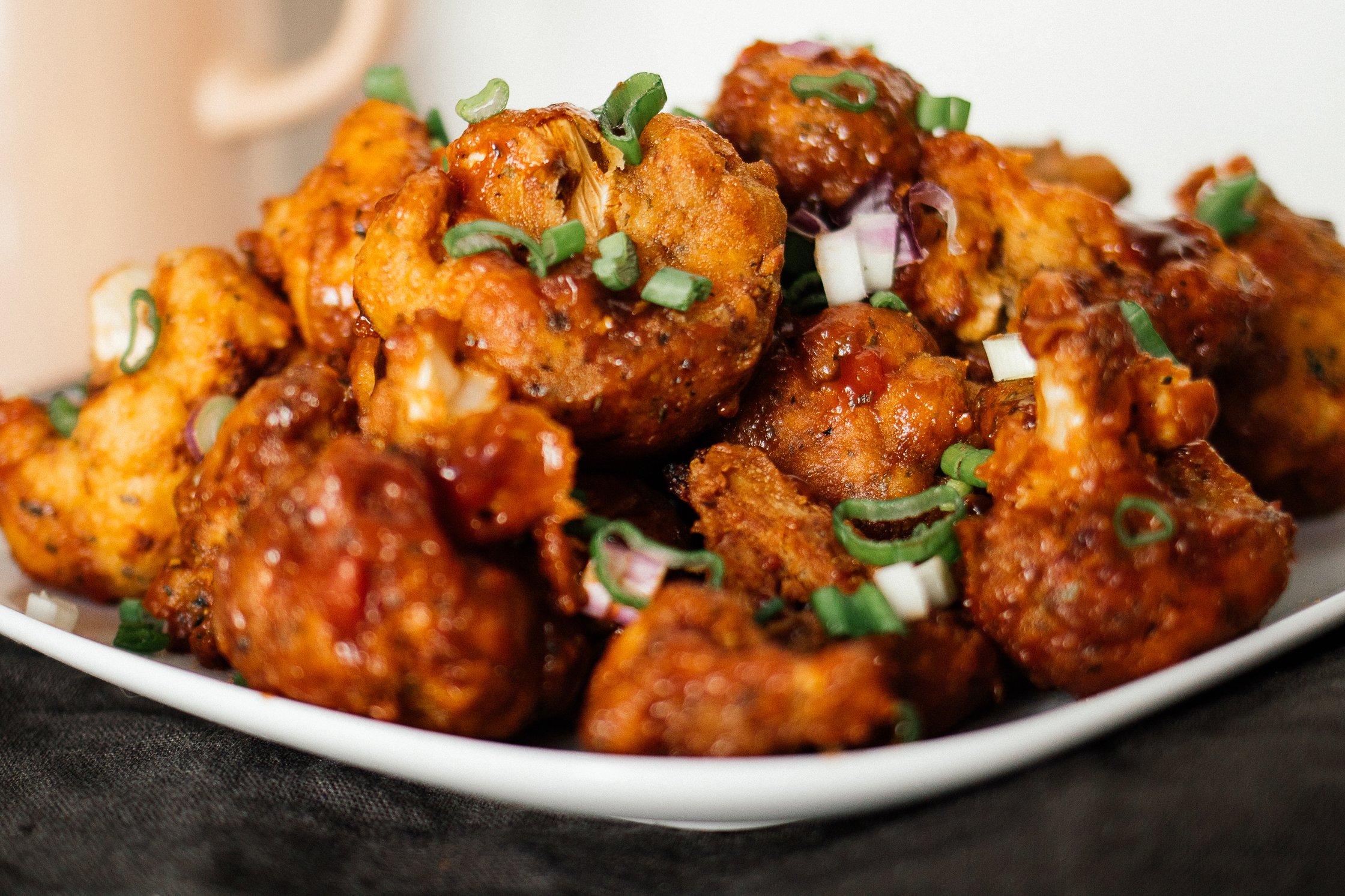 vegan cauliflower chicken wings are stacked on a palte