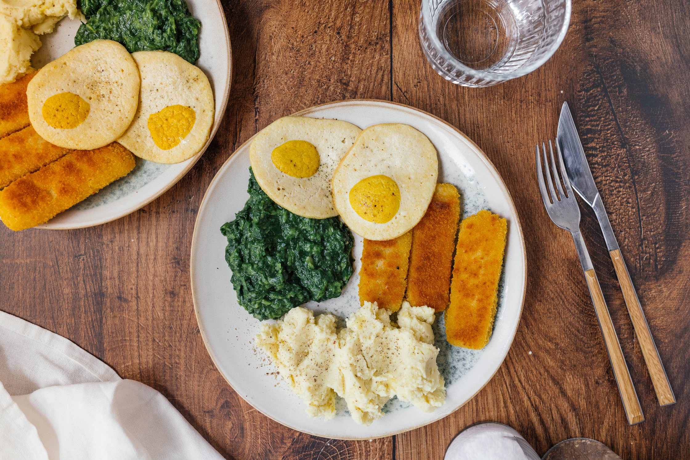 mashed potatoes with creamed spinach, vegan fried eggs and vegan fish fingers on a plate