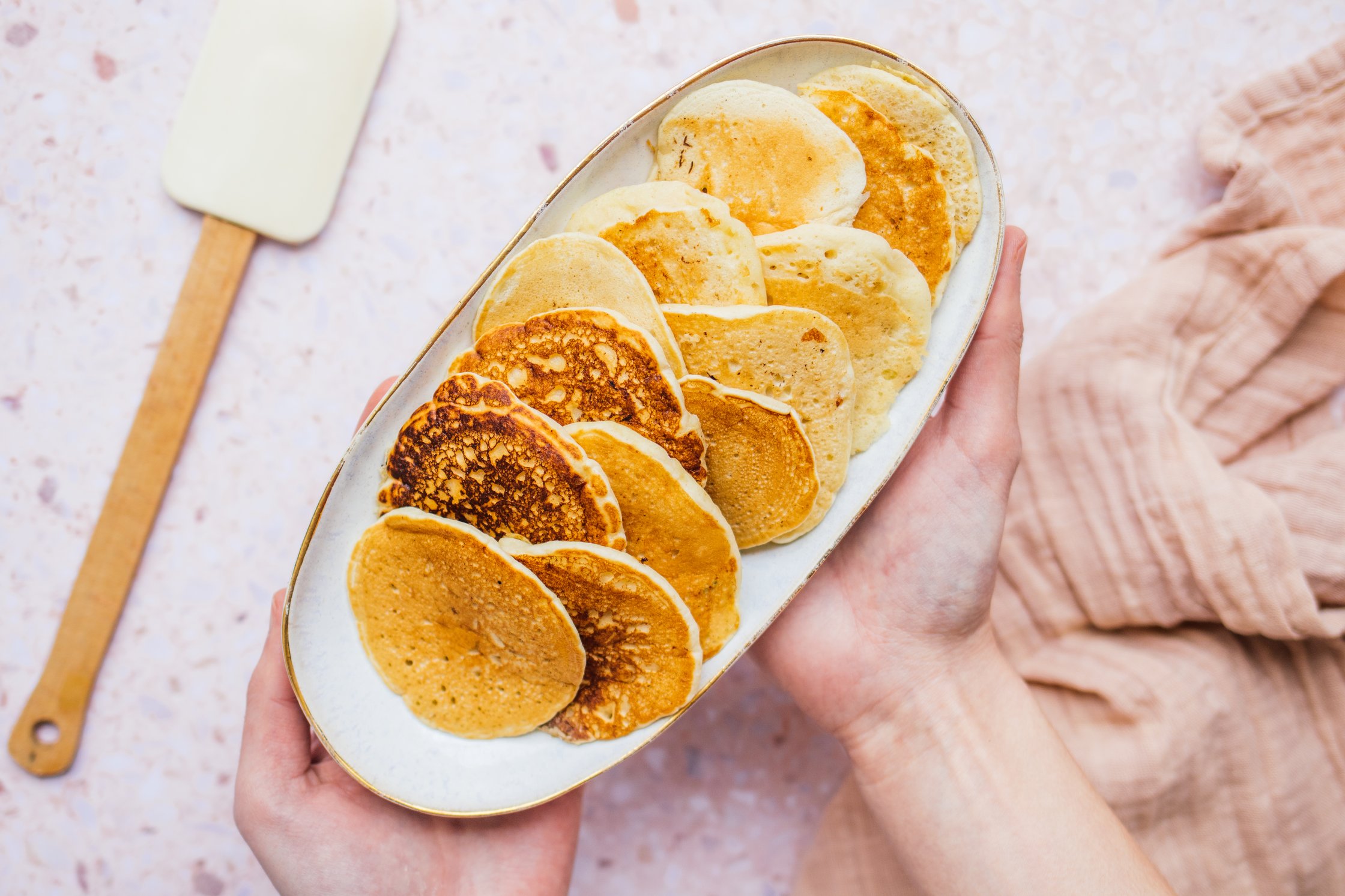 Hände halten vegane Pancakes auf einer Platte