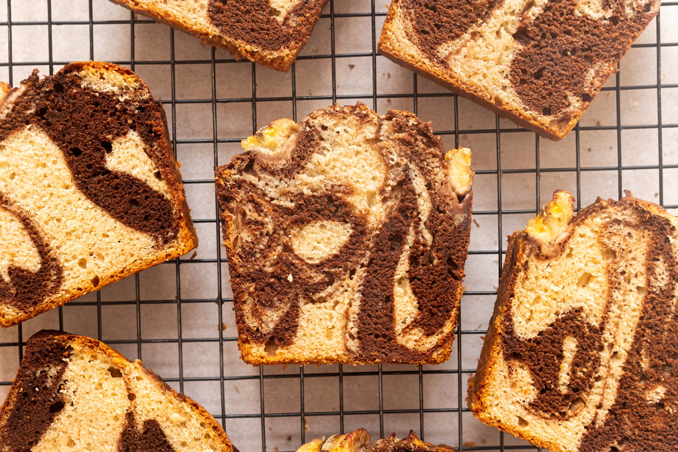 Many slices of marble banana bread on a cooling rack.