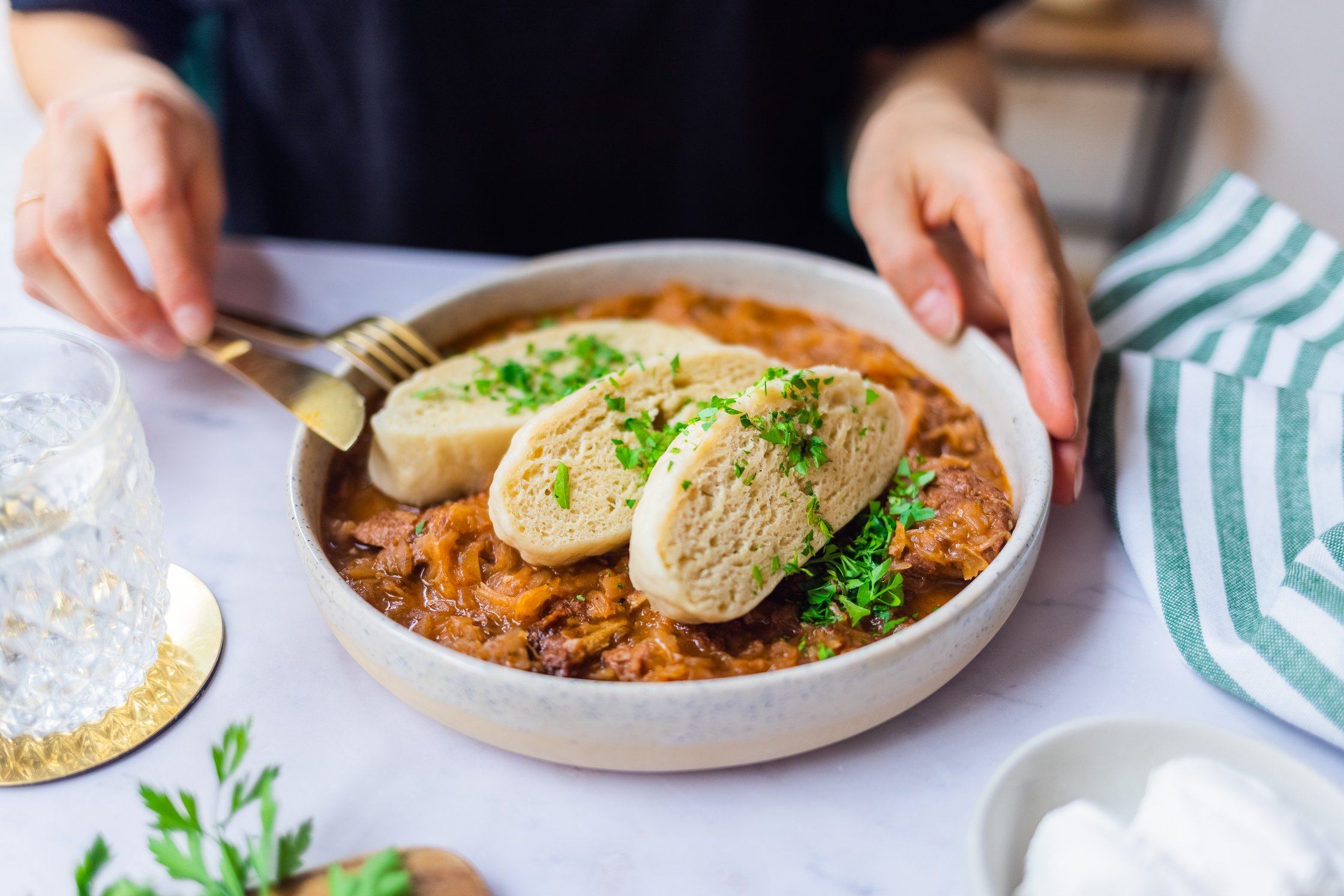 Vegan yeast dumplings with Szegedin Goulash (Hungarian Stew) are arranged on a plate.