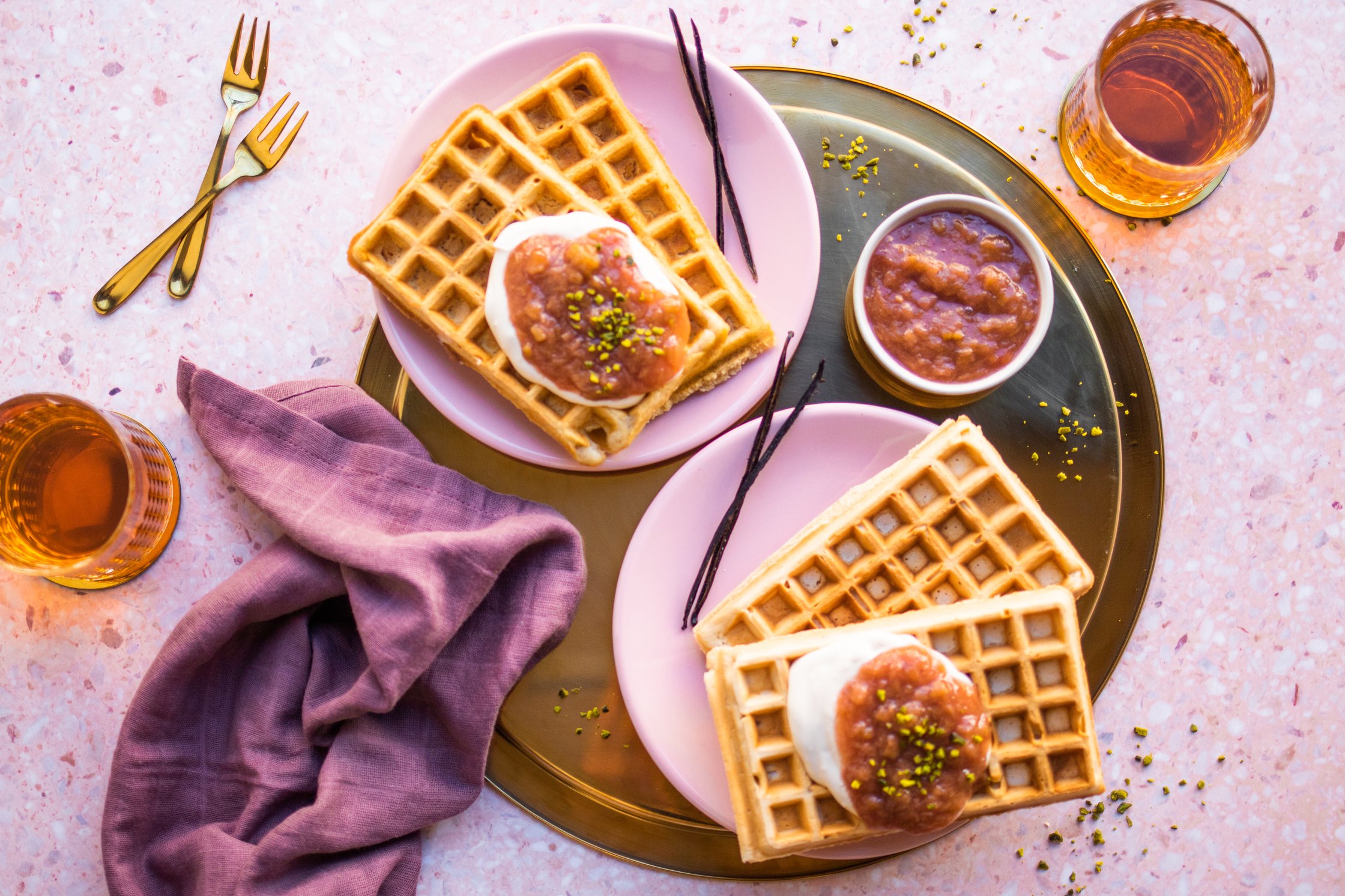 Vegan Vanilla Waffles with rhubarb compote laying next to rhubarb stacks