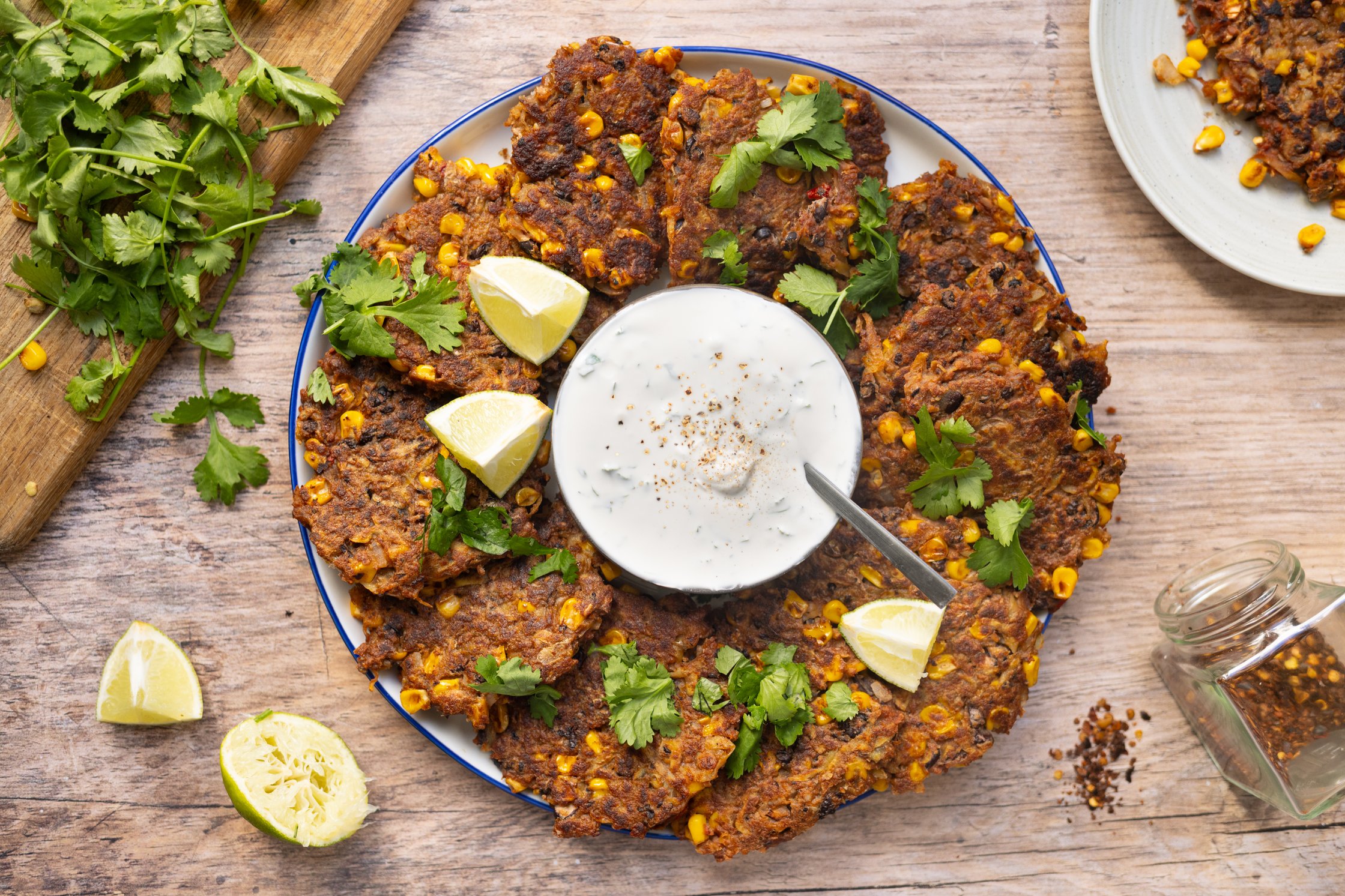 Chili sin carne fritters are arranged on a plate around a bowl of dip.