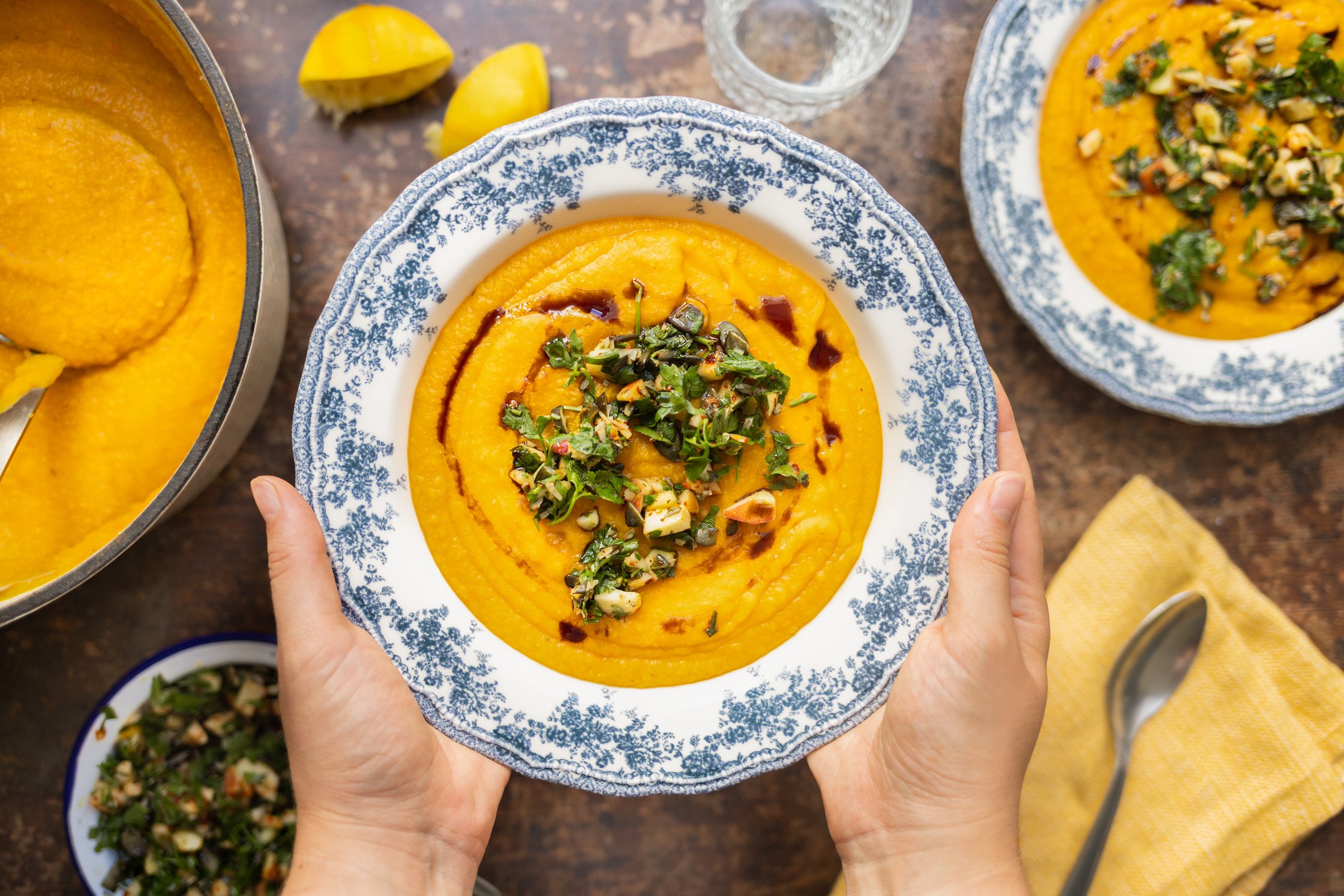 Zwei Hände halten eine volle Schüssel mit der Suppe.