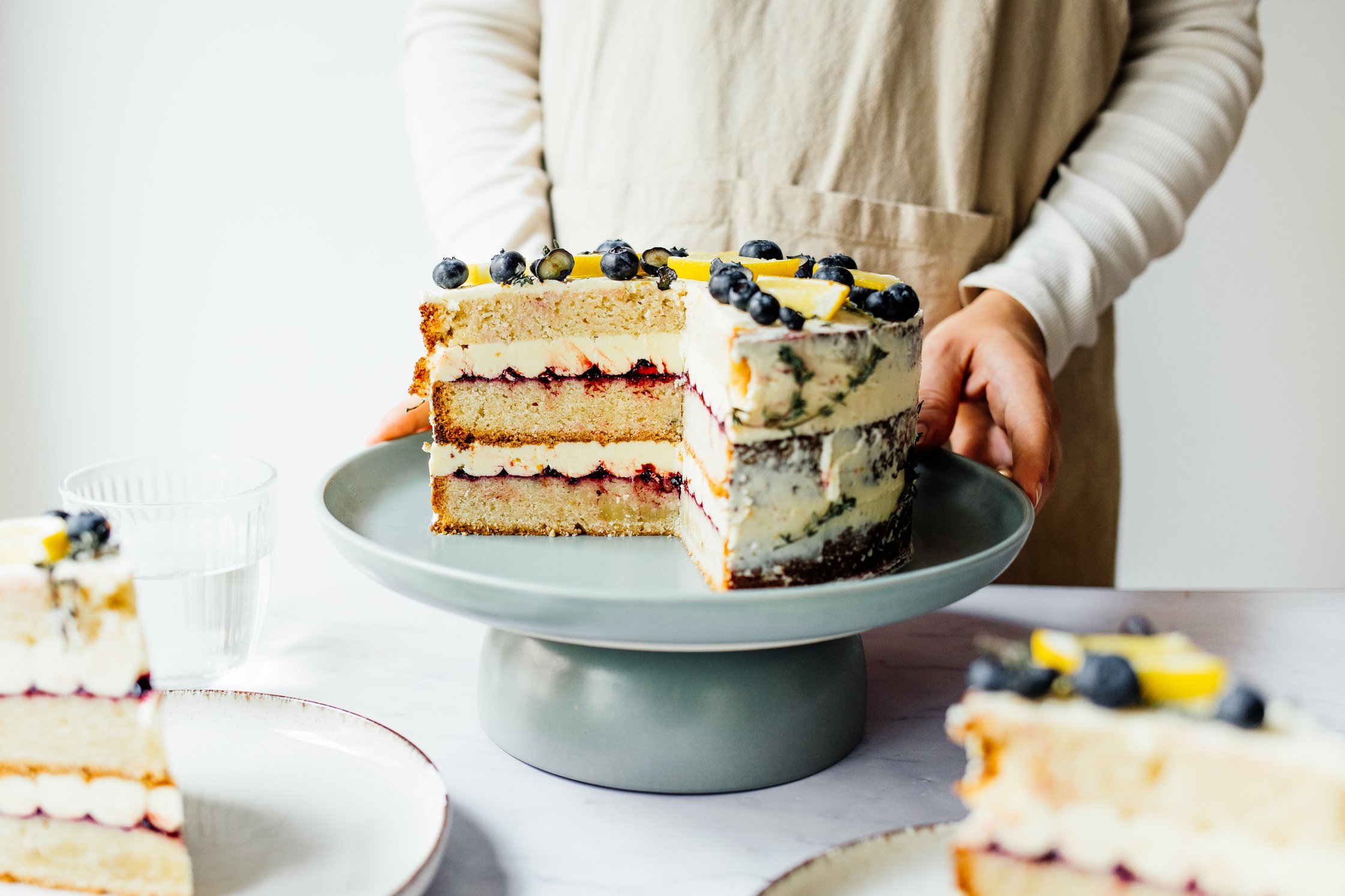 vegan naked cake on a cake platter, decorated with blueberries and thyme