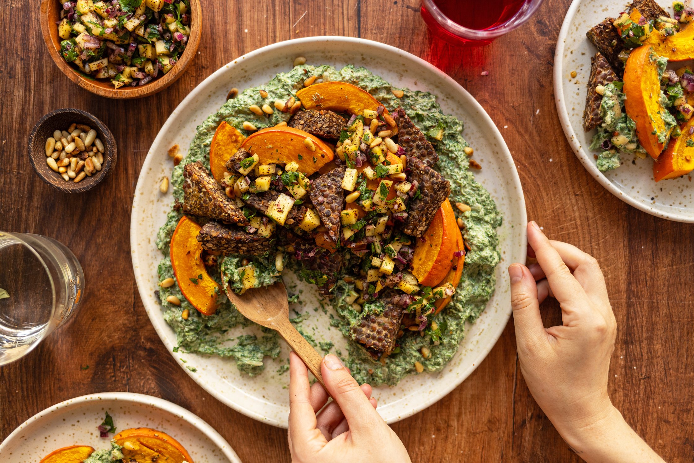 Kürbis und Tempeh aus dem Ofen mit würzigem Rahmspinat und Mango-Salsa wird auf einem tisch serviert
