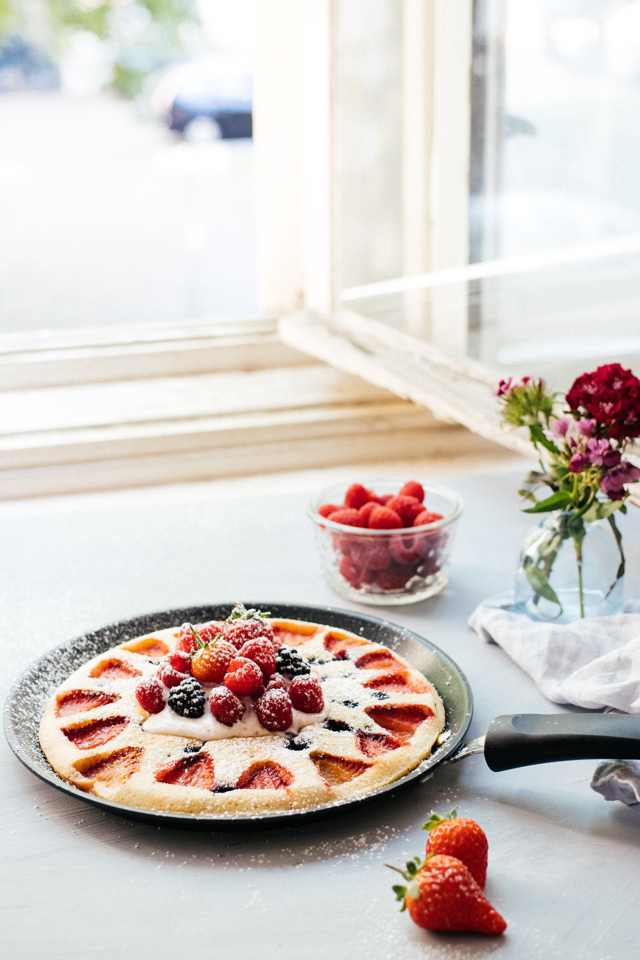 veganer Pfannen-Pancake mit Beeren vor einem Fenster