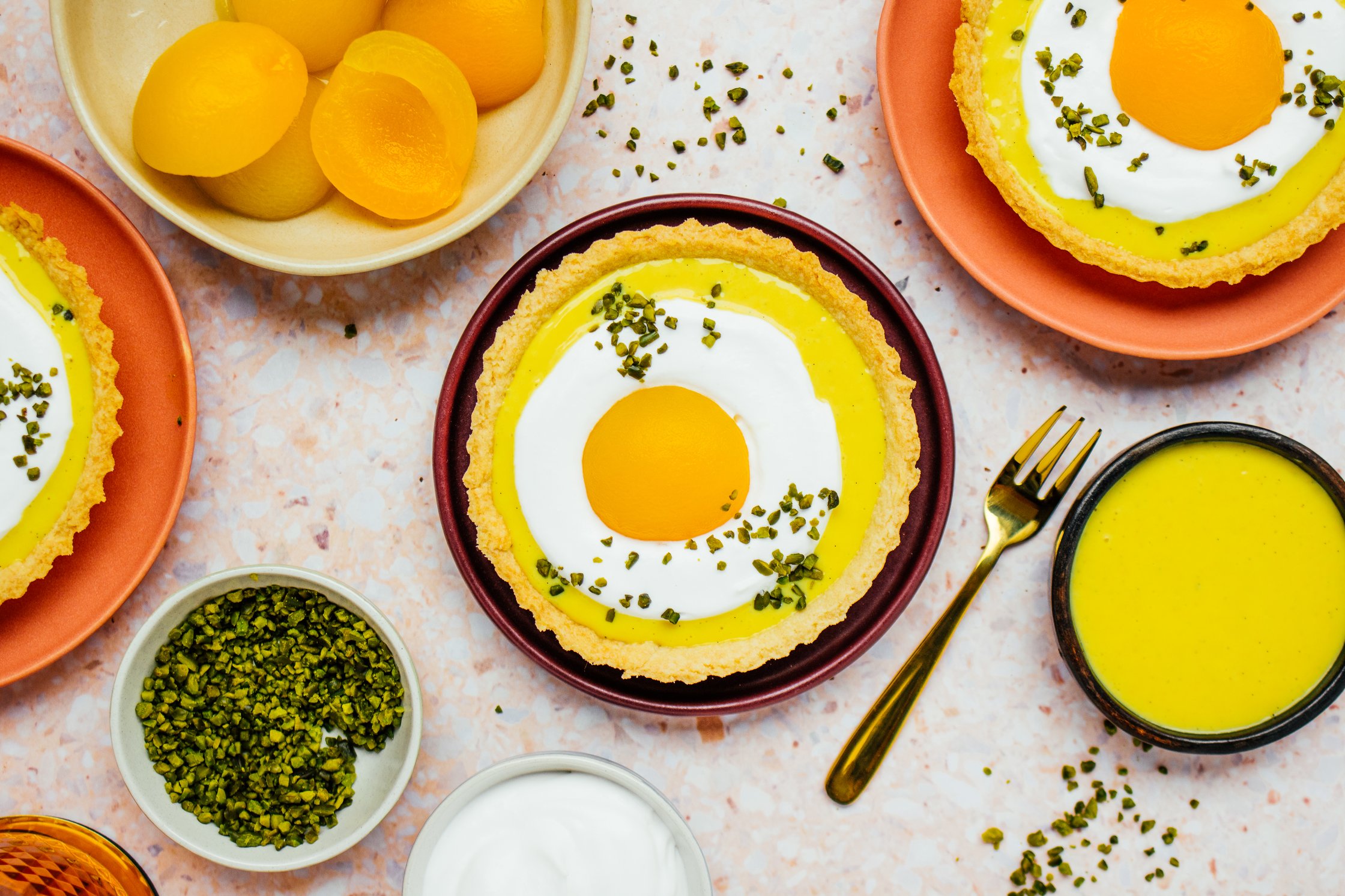 Mehrere Vegane Eierlikör Oster Tartelettes mit Aprikosen, veganem Eierlikör und Sahne-Topping auf Tellern