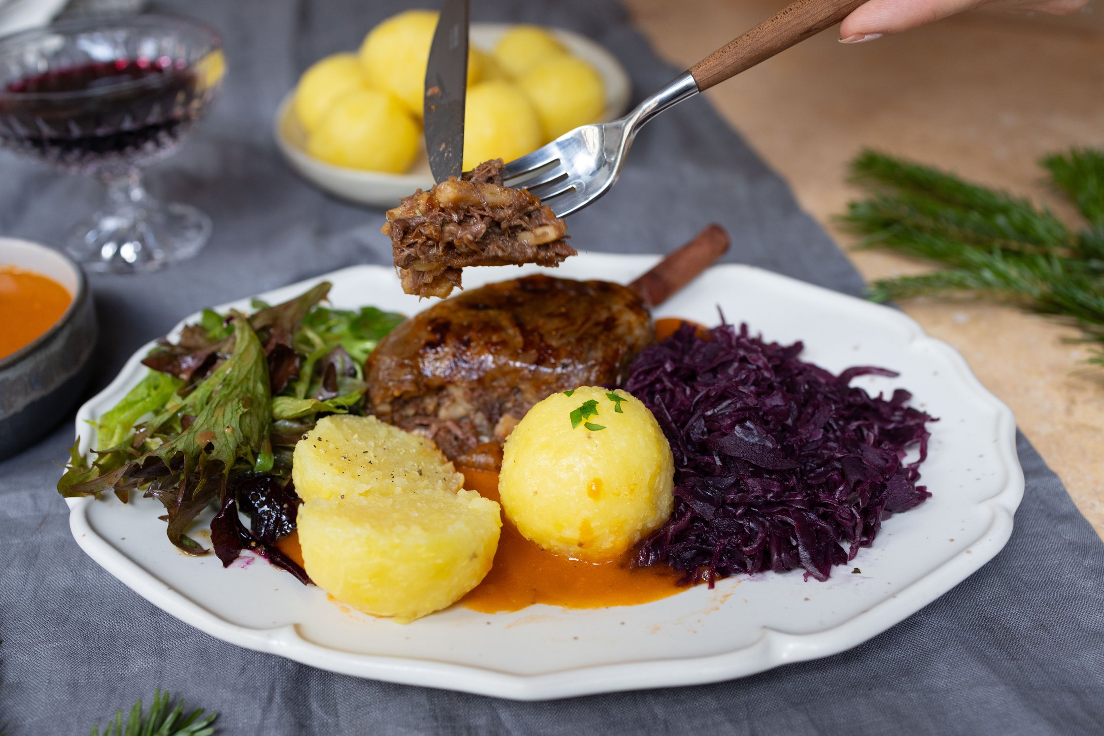 Keule, Klöße, Rotkraut und Salat auf einem Teller