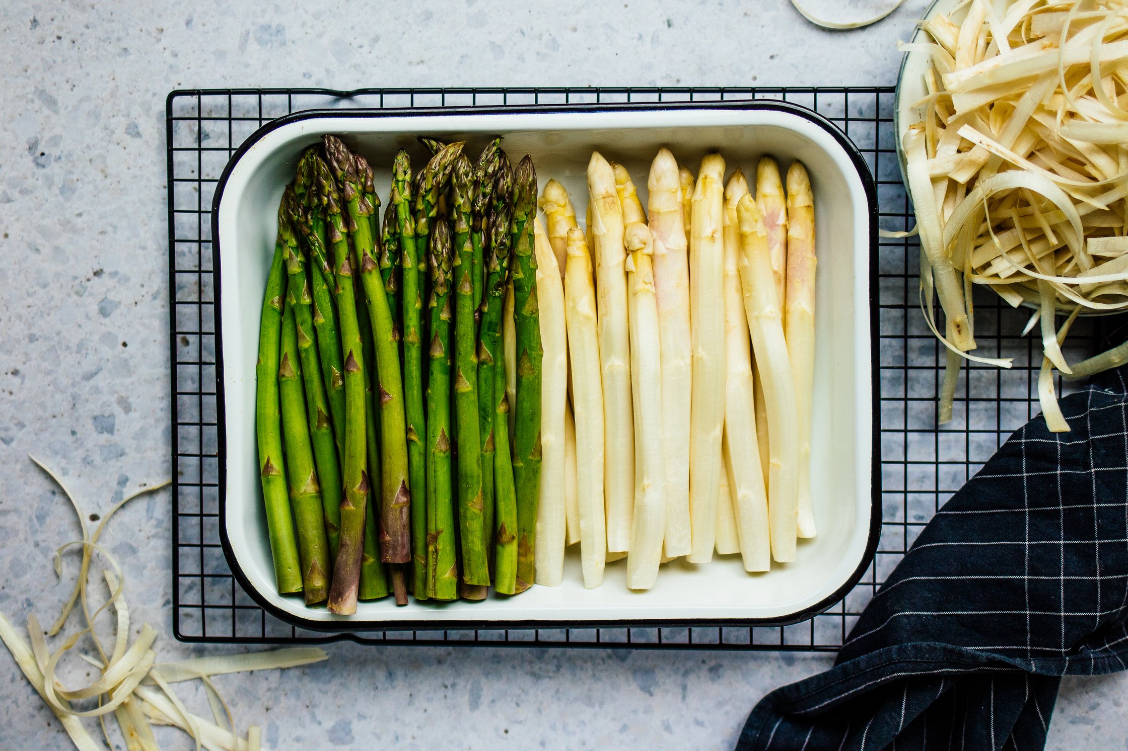 grüner und weißer Spargel in einer Auflaufform auf einem Rost