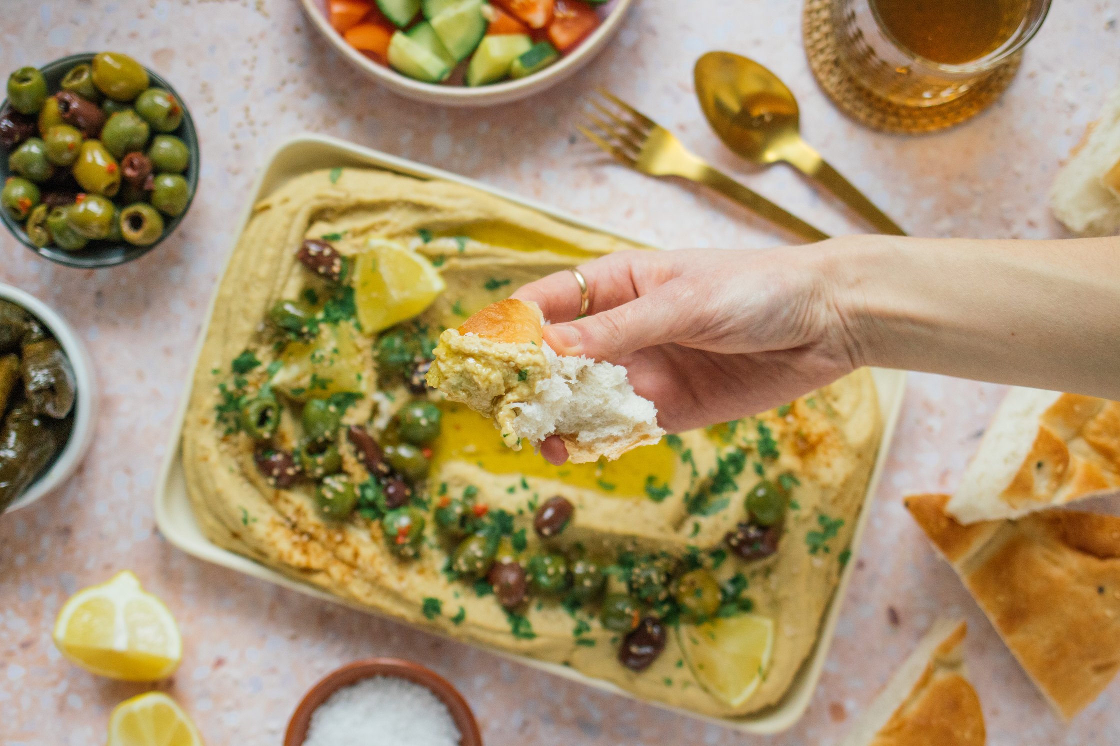 hand holding hummus dipped flatbread