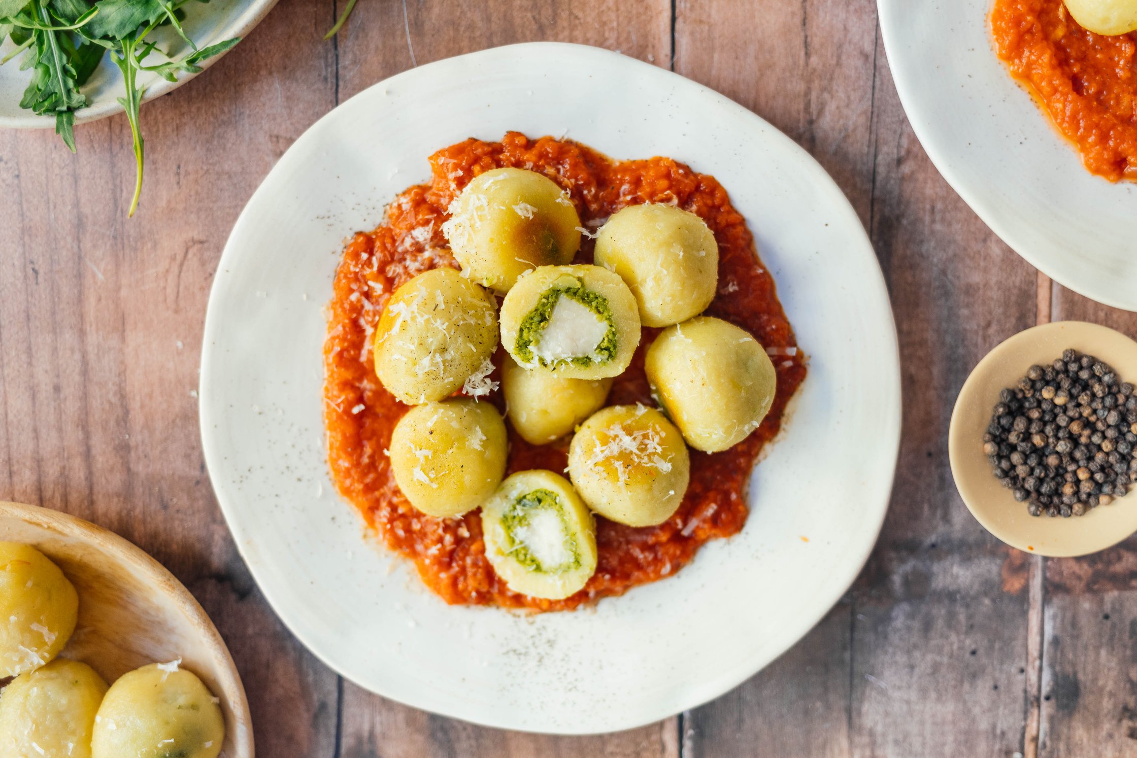 vegan stuffed gnocchi on tomato sauce with vegan parmesan cheese arranged on a plate