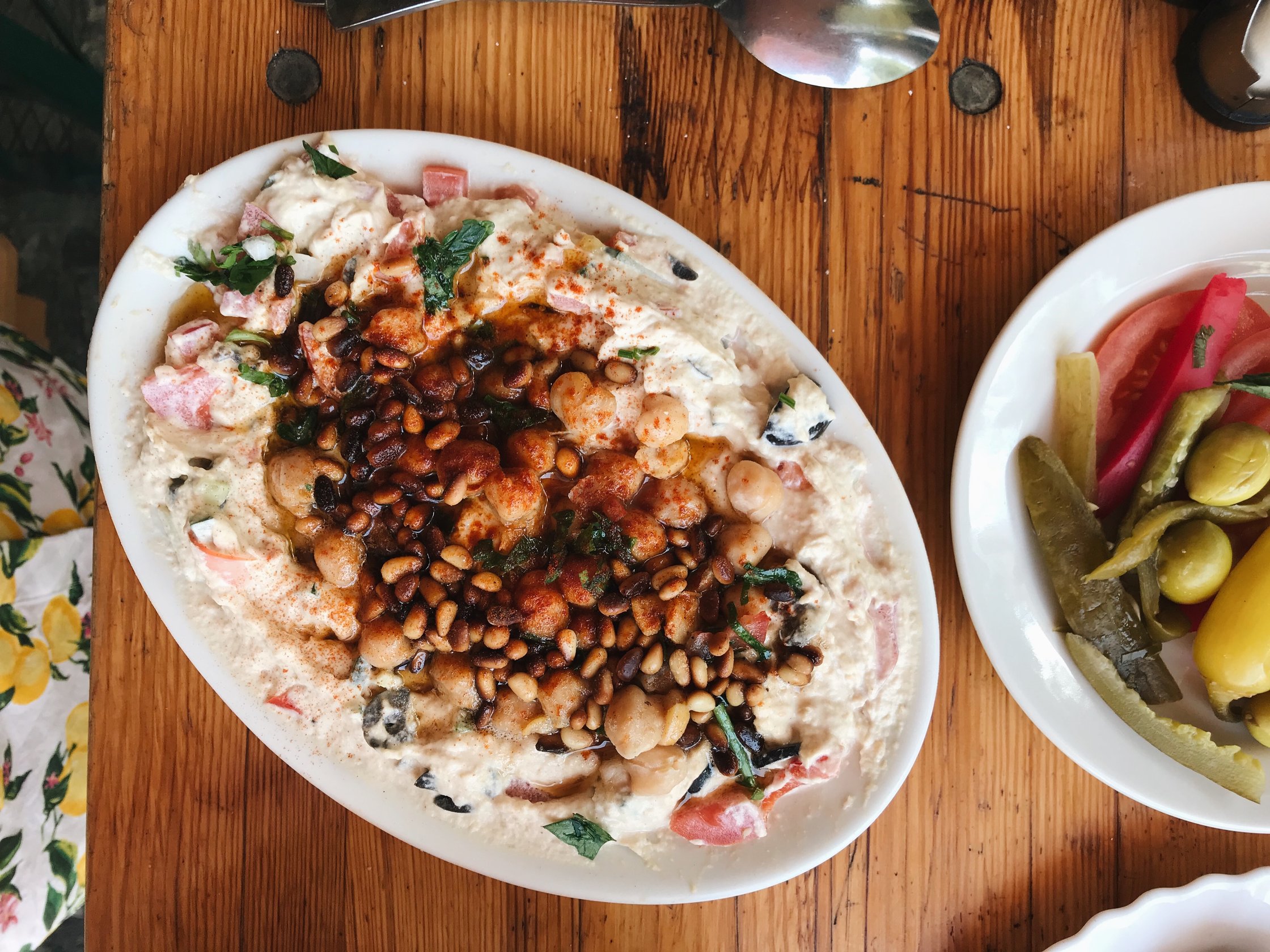 plate of hummus with vegetables and pine nuts from al pasha