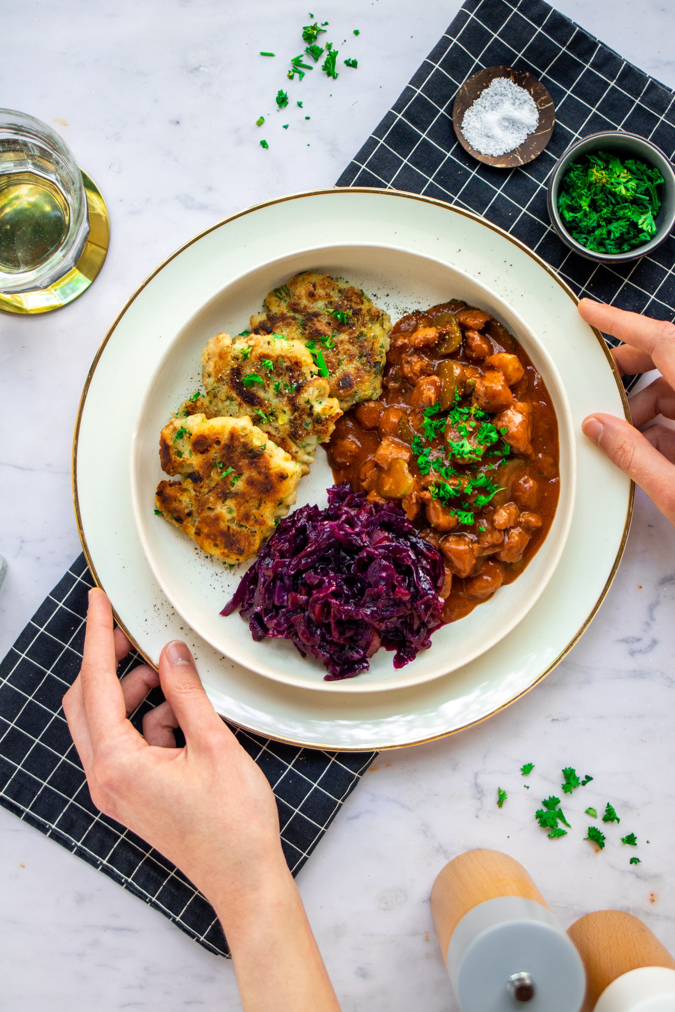 Vegan goulash with pan dumplings and red cabbage served on a white plate