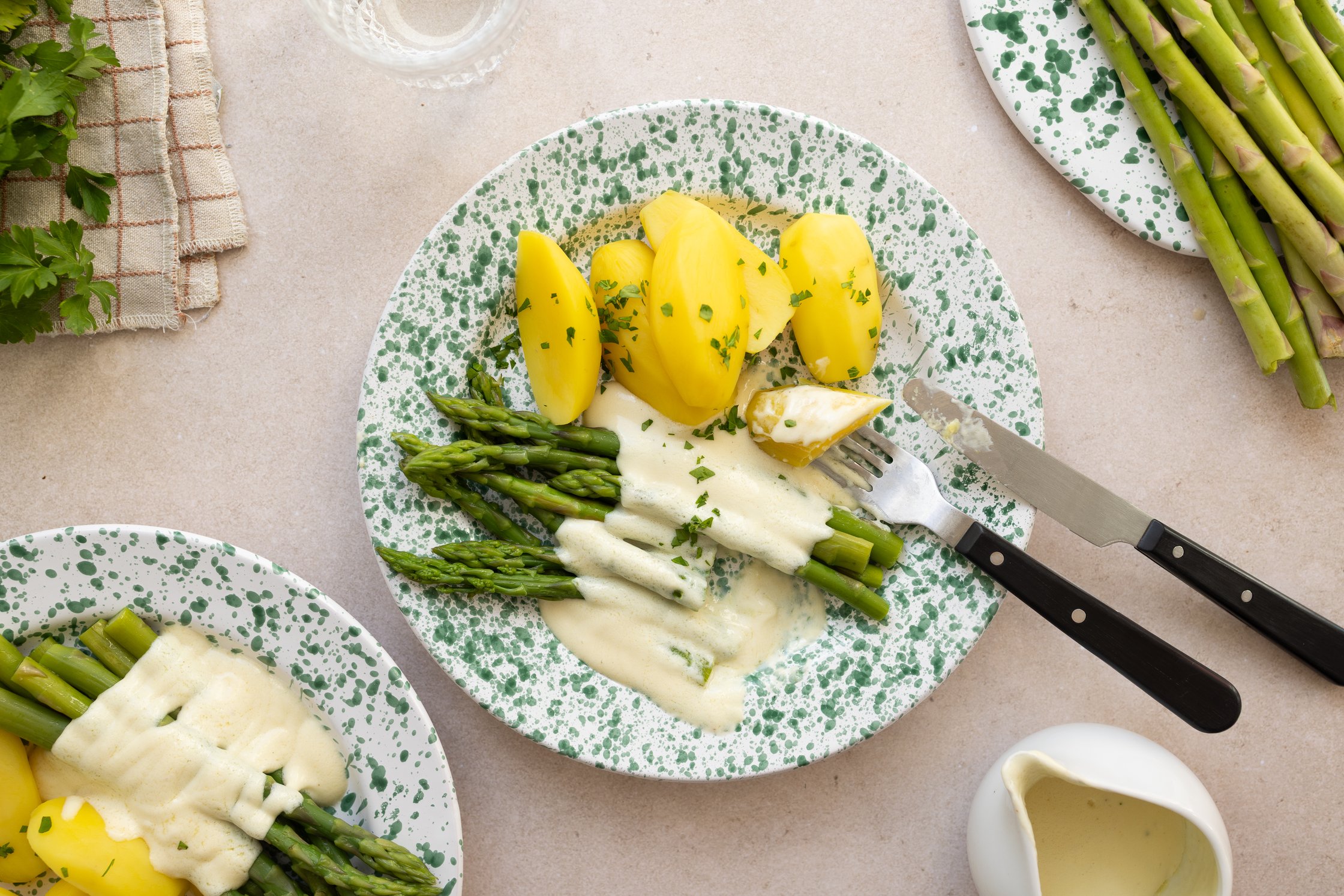Spargel, Kartoffeln und vegane Sauce Hollandaise auf einem hellen Teller