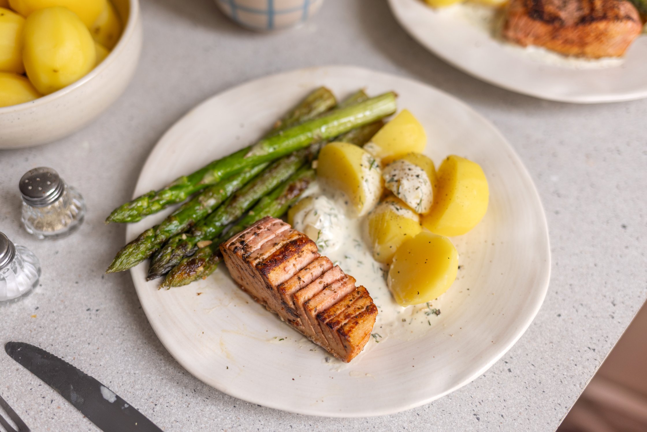 ein teller mit Veganem Tofu-Lachs mit gebratenem Spargel, Kartoffeln und Dill-Sahne-Soße