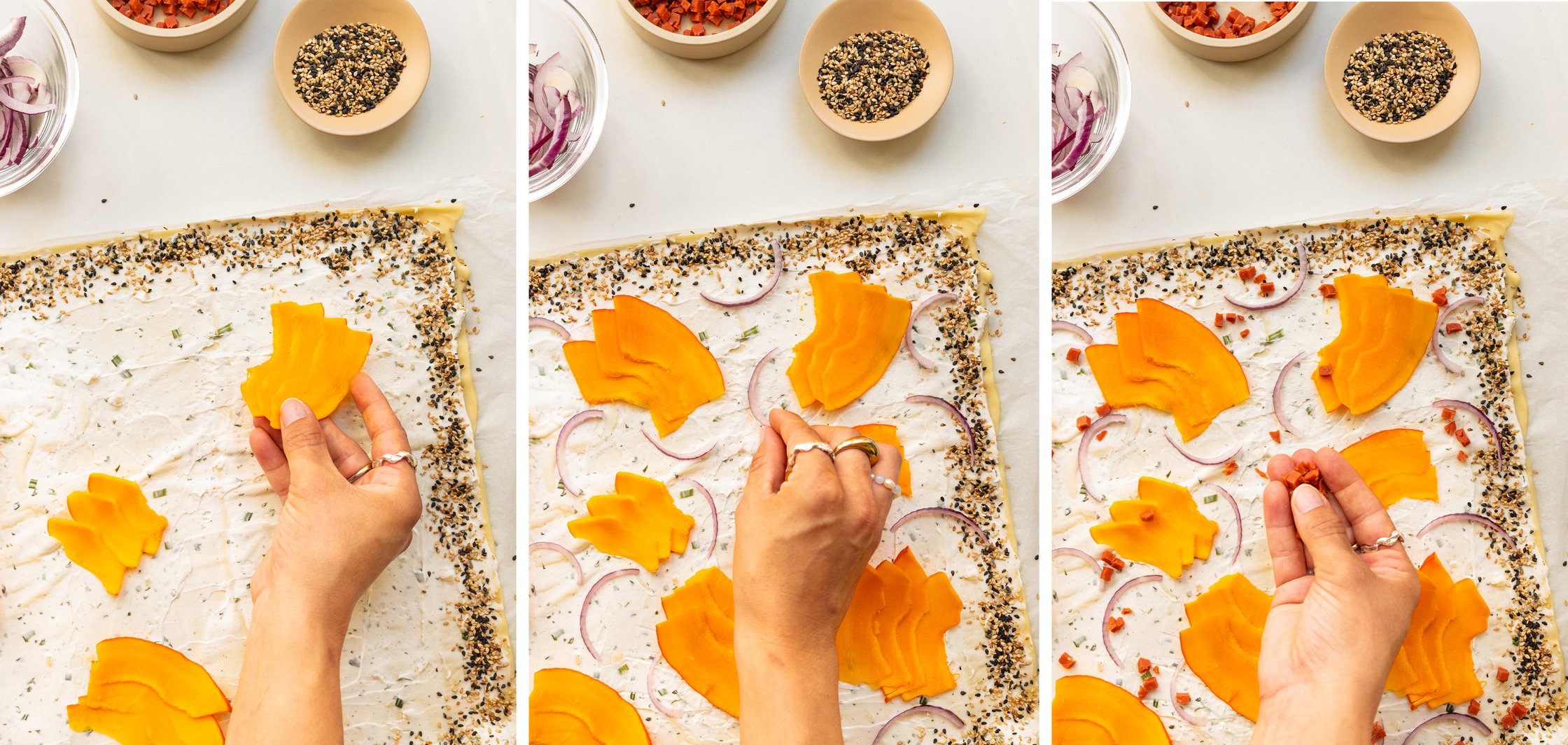 Hands topping a tarte flambée base with pumpkin slices, thin onion rings, and vegan bacon.