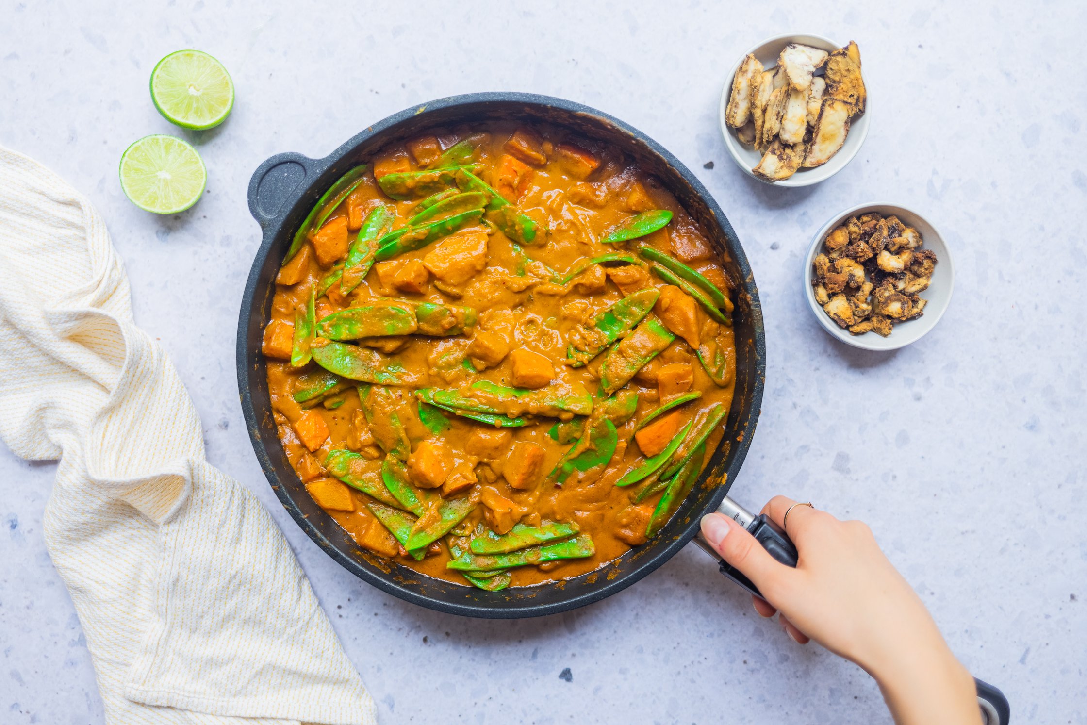 Vegan pumpkin curry with sugar snaps in a pan against a light background