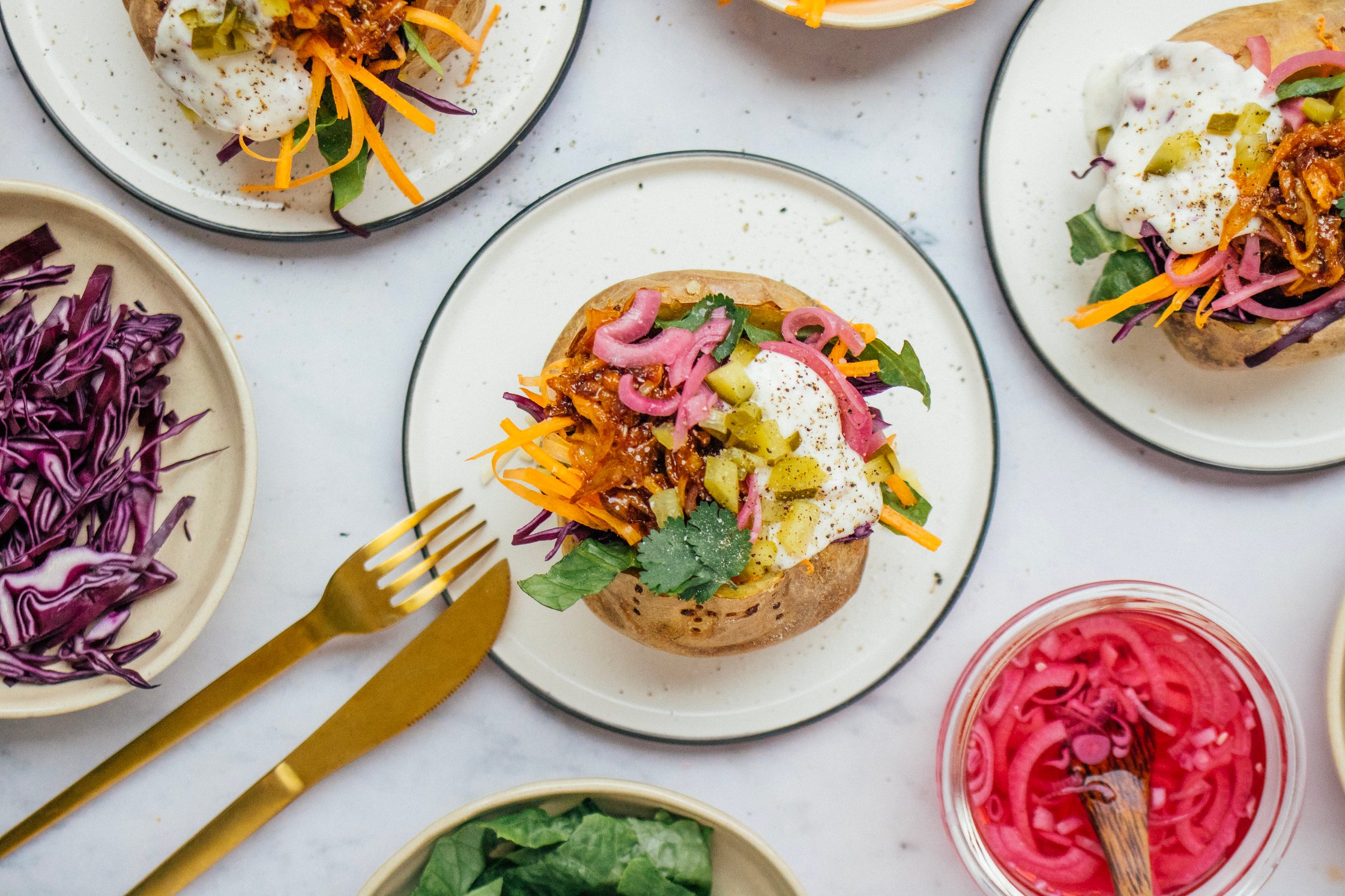 Stuffed vegan kumpir potato with fresh veggies, pickled onions, pickles, salad, vegan joghurt dip and pulled mushrooms