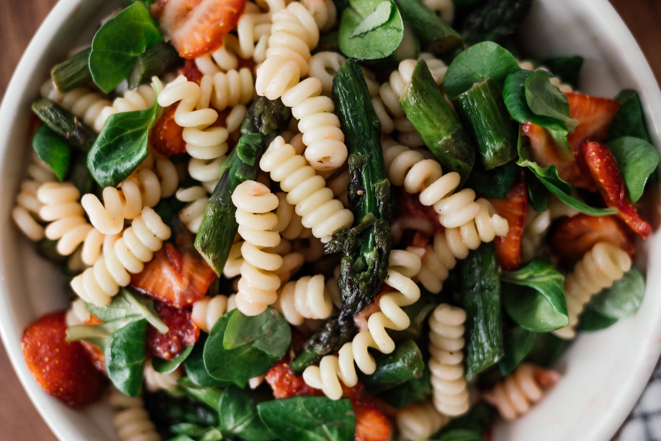 close up of a vegan asparagus pasta salad with strawberries