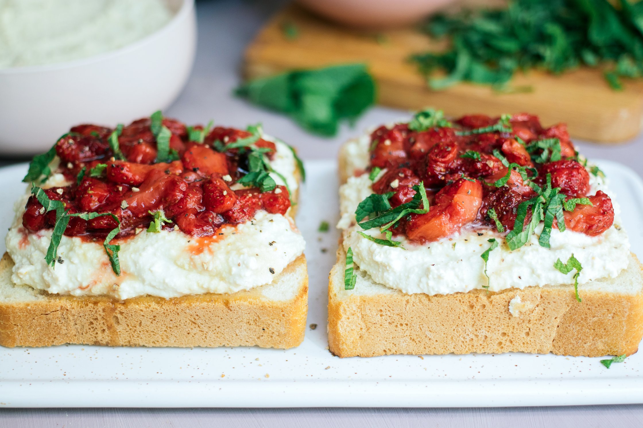 Frühstückstoasts mit veganem Ricotta und gebackenen Erdbeeren serviert auf einem teller