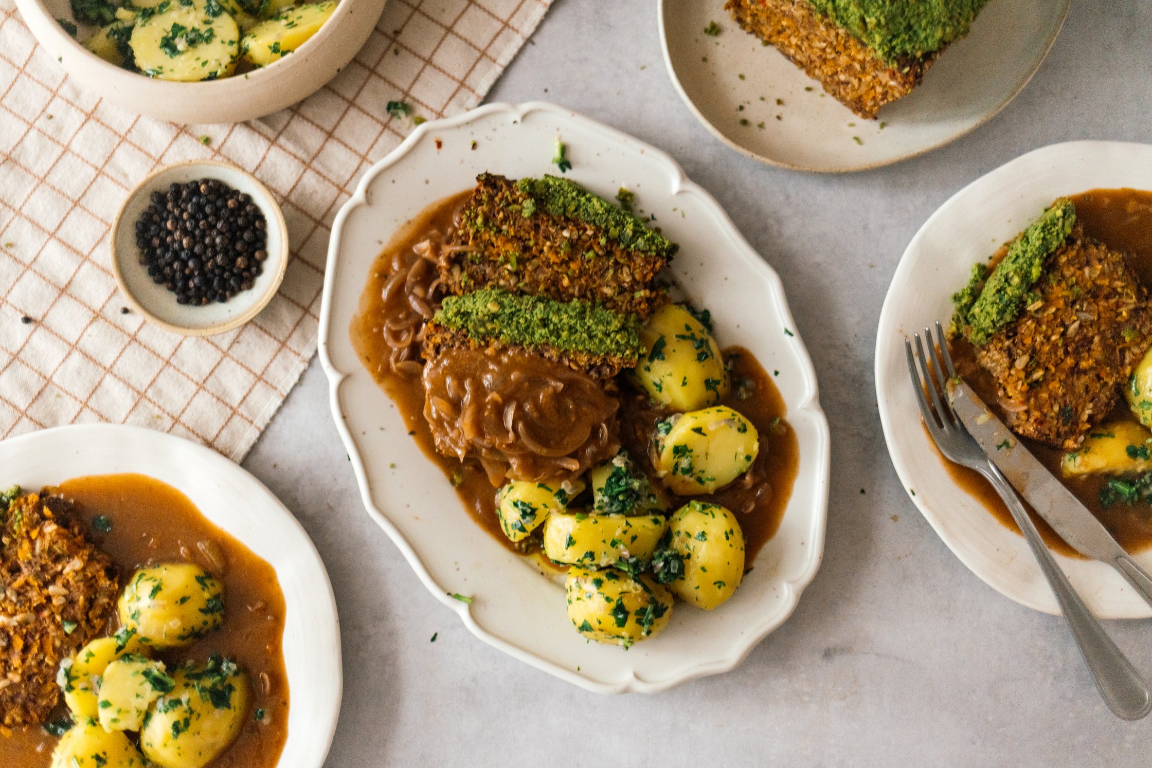 Vegan Herb-Crusted Roast with Parsley Potatoes and Onion Gravy on the table