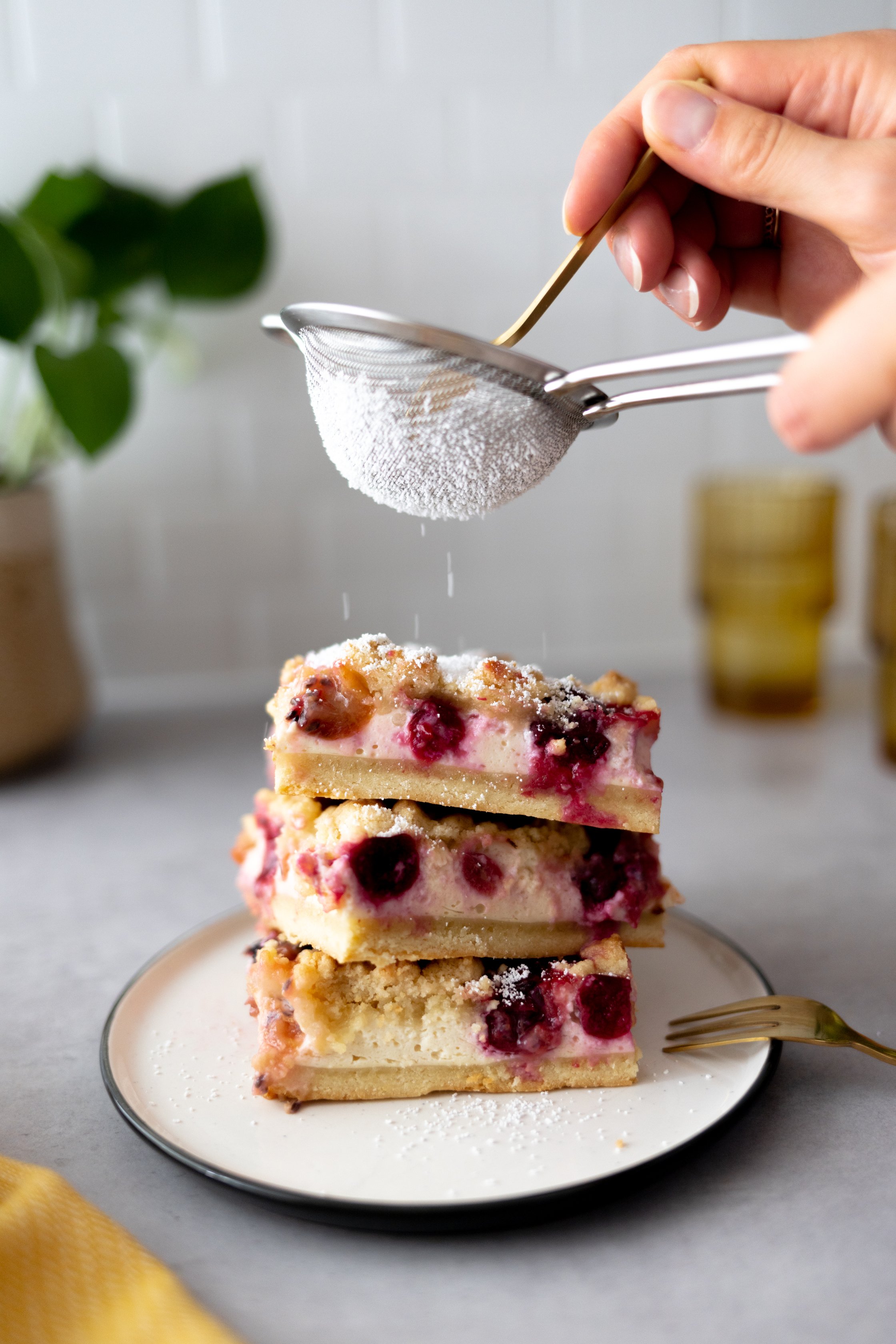 Vegan crumble cake stacked on a plate, is decorated with powdered sugar