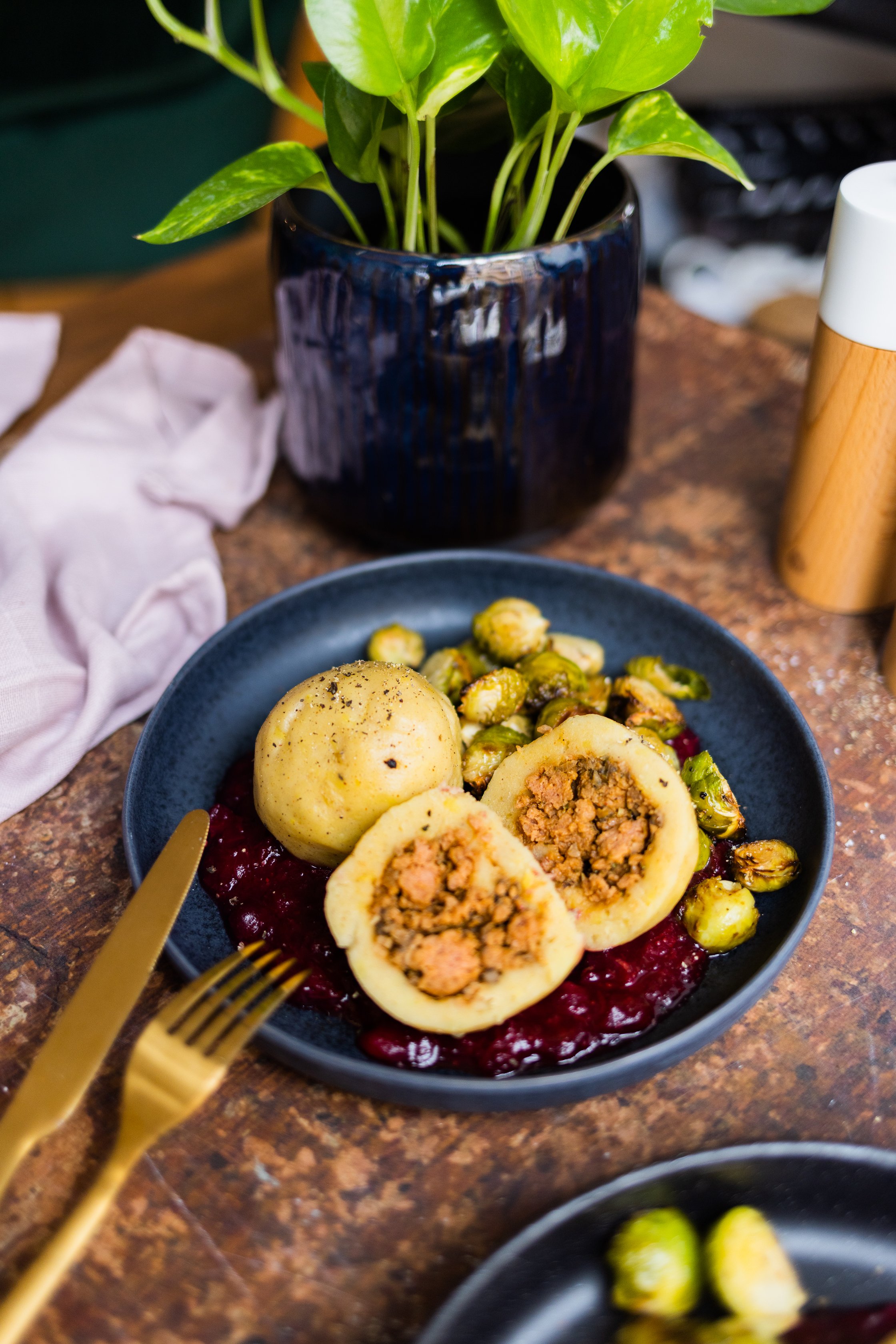 Vegane gefüllte Knödel mit gebackenem und karamellisierem Rosenkohl und Cranberrysoße, Salz- und Pfefferstreuer